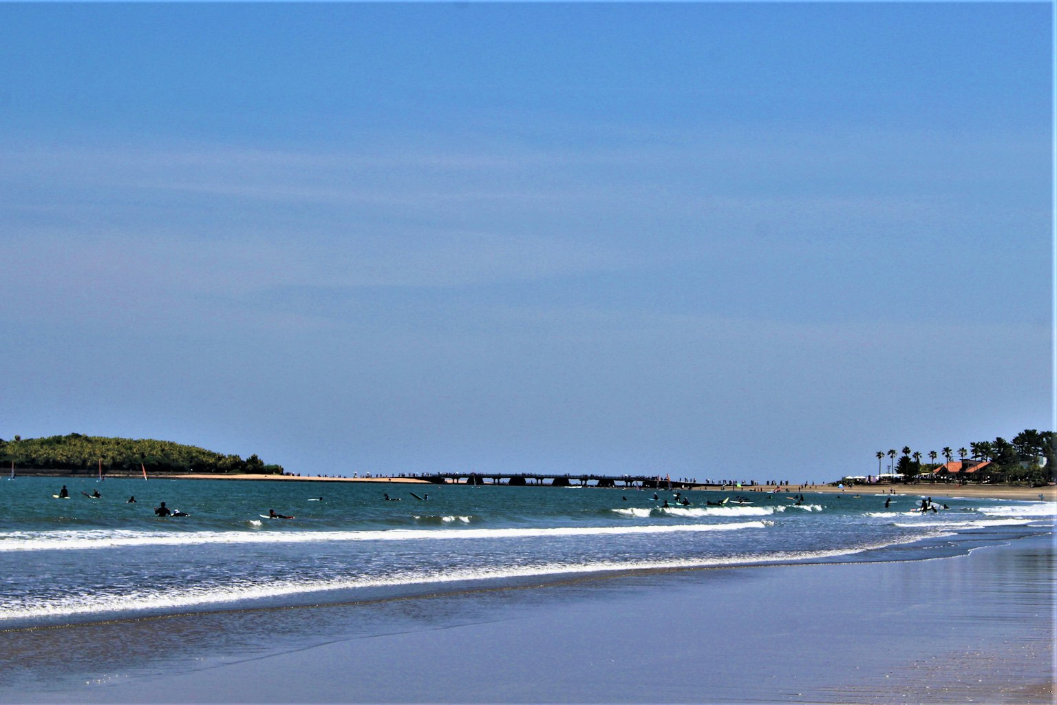 Malersicher Strandblick mit blauem Meer und Surfern, die die Wellen genießen