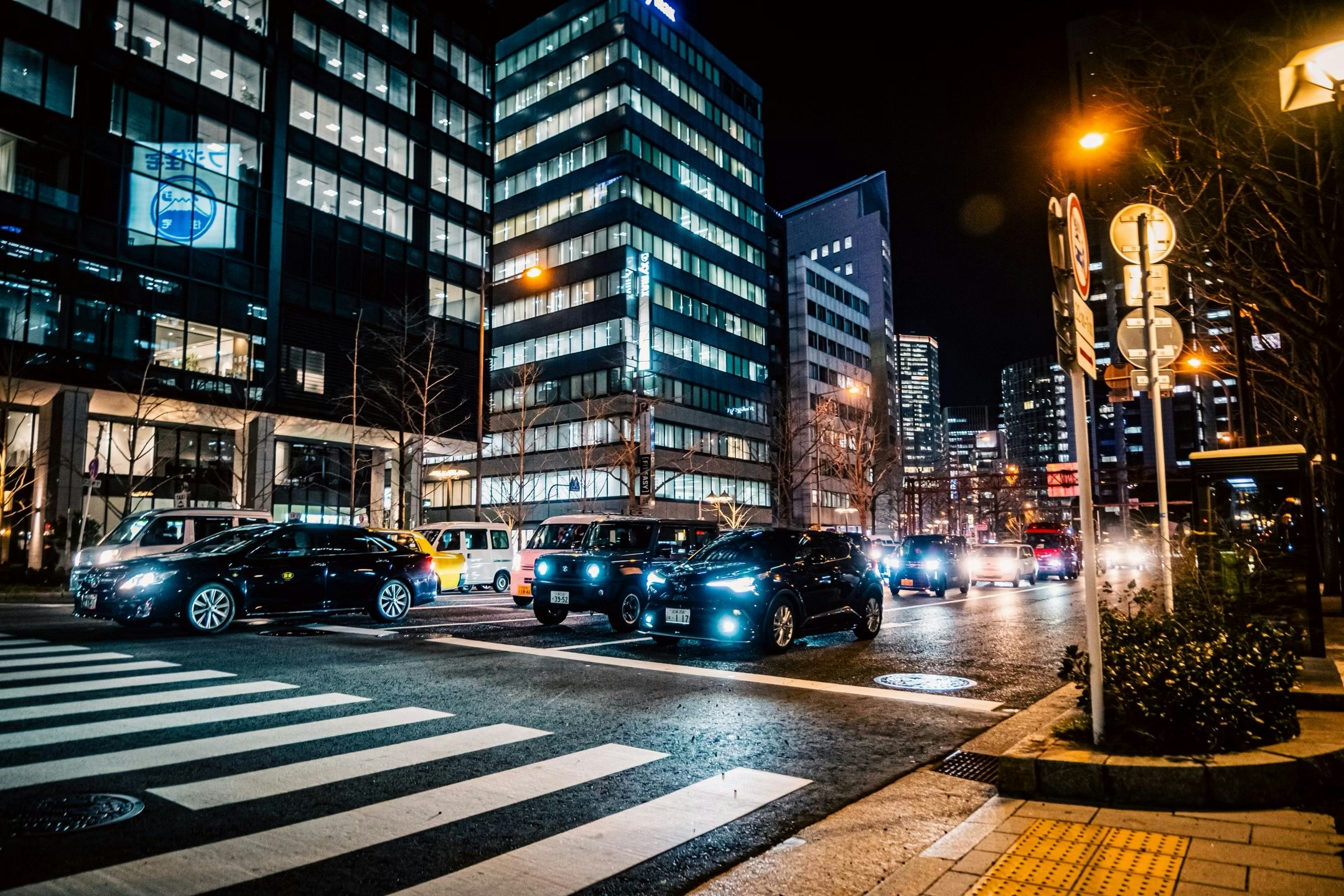 夜の交差点で並ぶ車と高層ビルの街並み