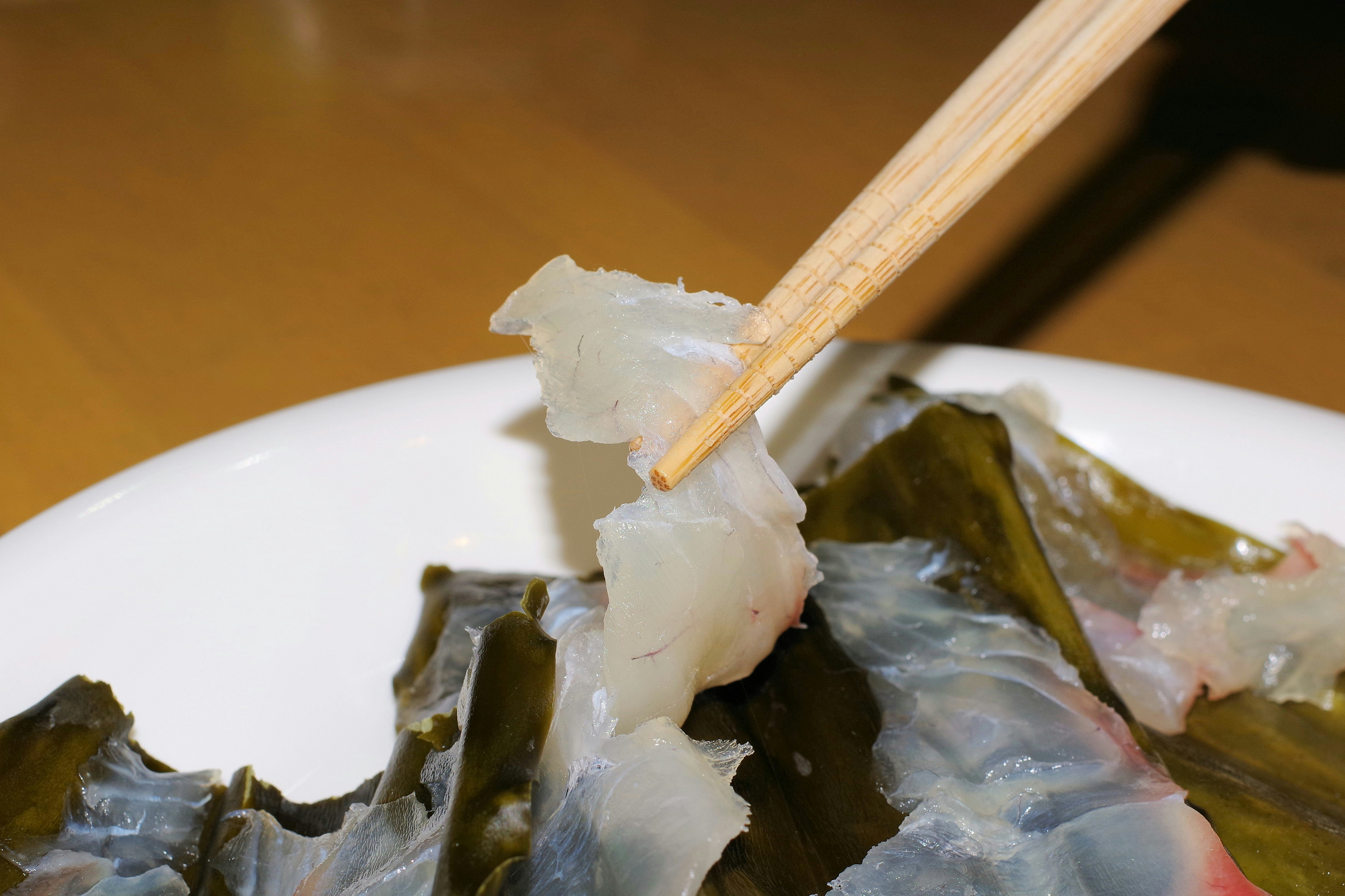 筷子夾起的生魚片拼盤