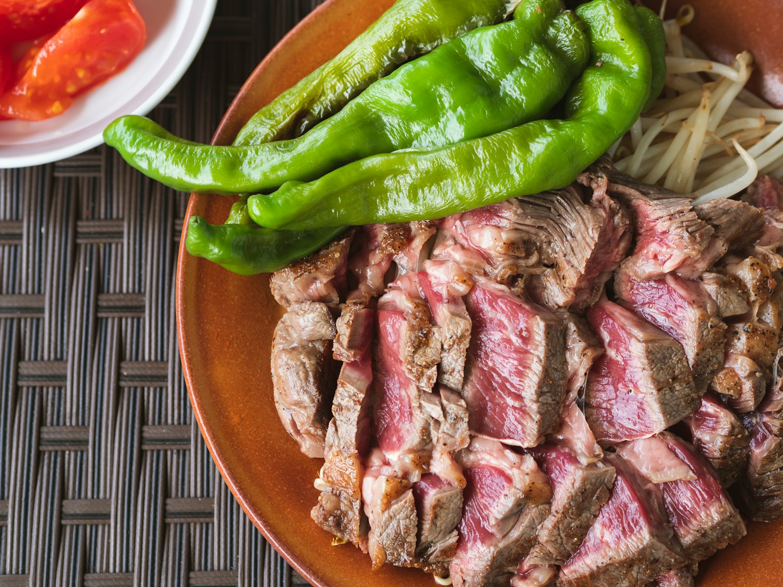 In Scheiben geschnittenes Steak mit grünen Paprika und Zwiebeln serviert
