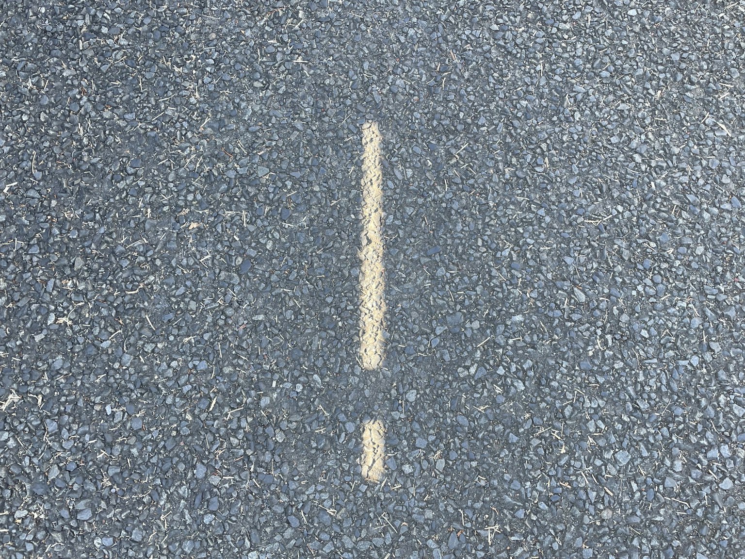 Yellow exclamation mark painted on asphalt
