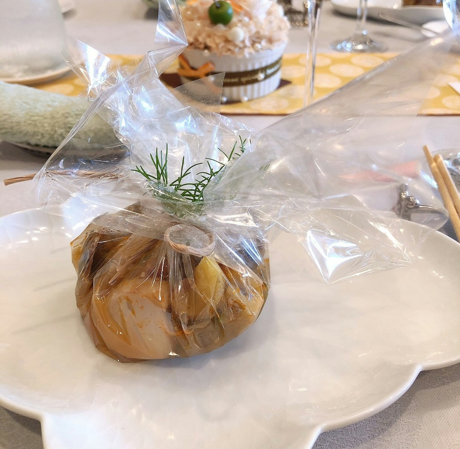 一个盘子上有用透明塑料包裹的食材，上面放着一根莳萝