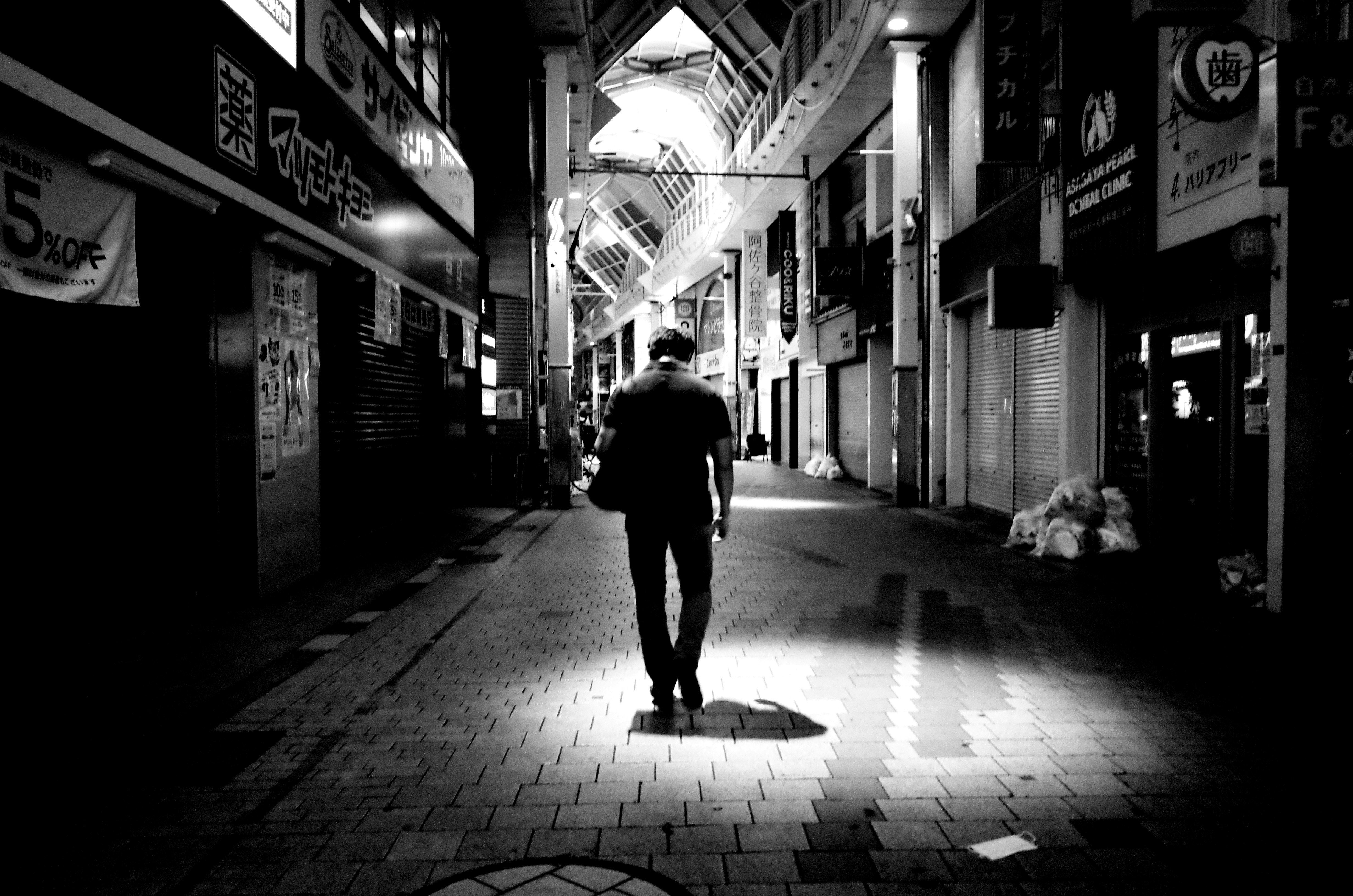 路地のモノクロ商店街で歩く人物のシルエット