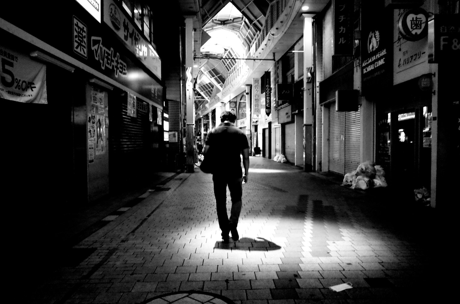 在昏暗小巷中行走的人影朝着更明亮的区域走去