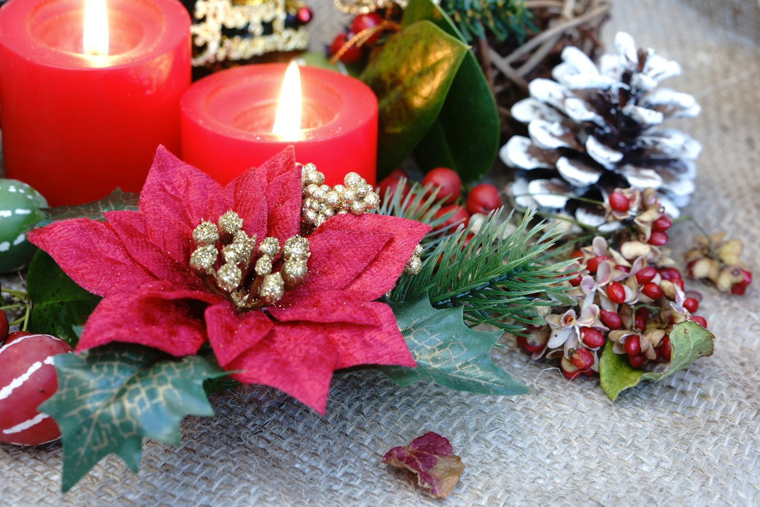 Dekorasi poinsettia merah dan kerucut pinus dengan lilin