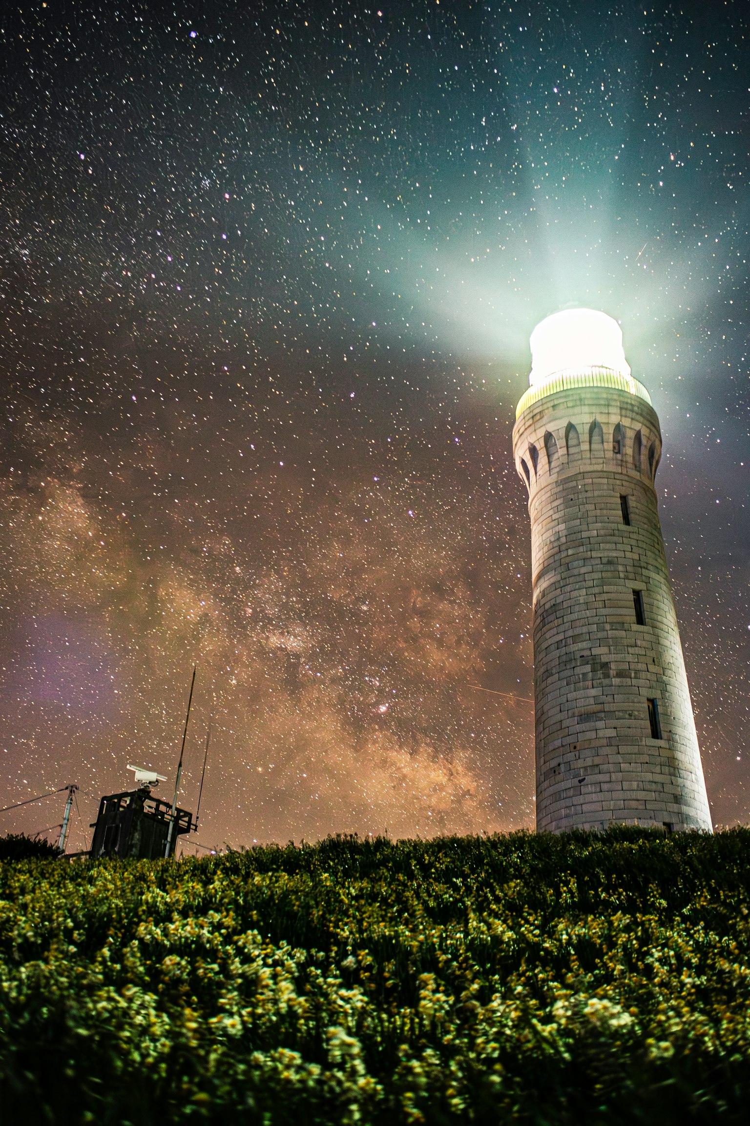 Faro illuminato sotto un cielo stellato con la Via Lattea visibile
