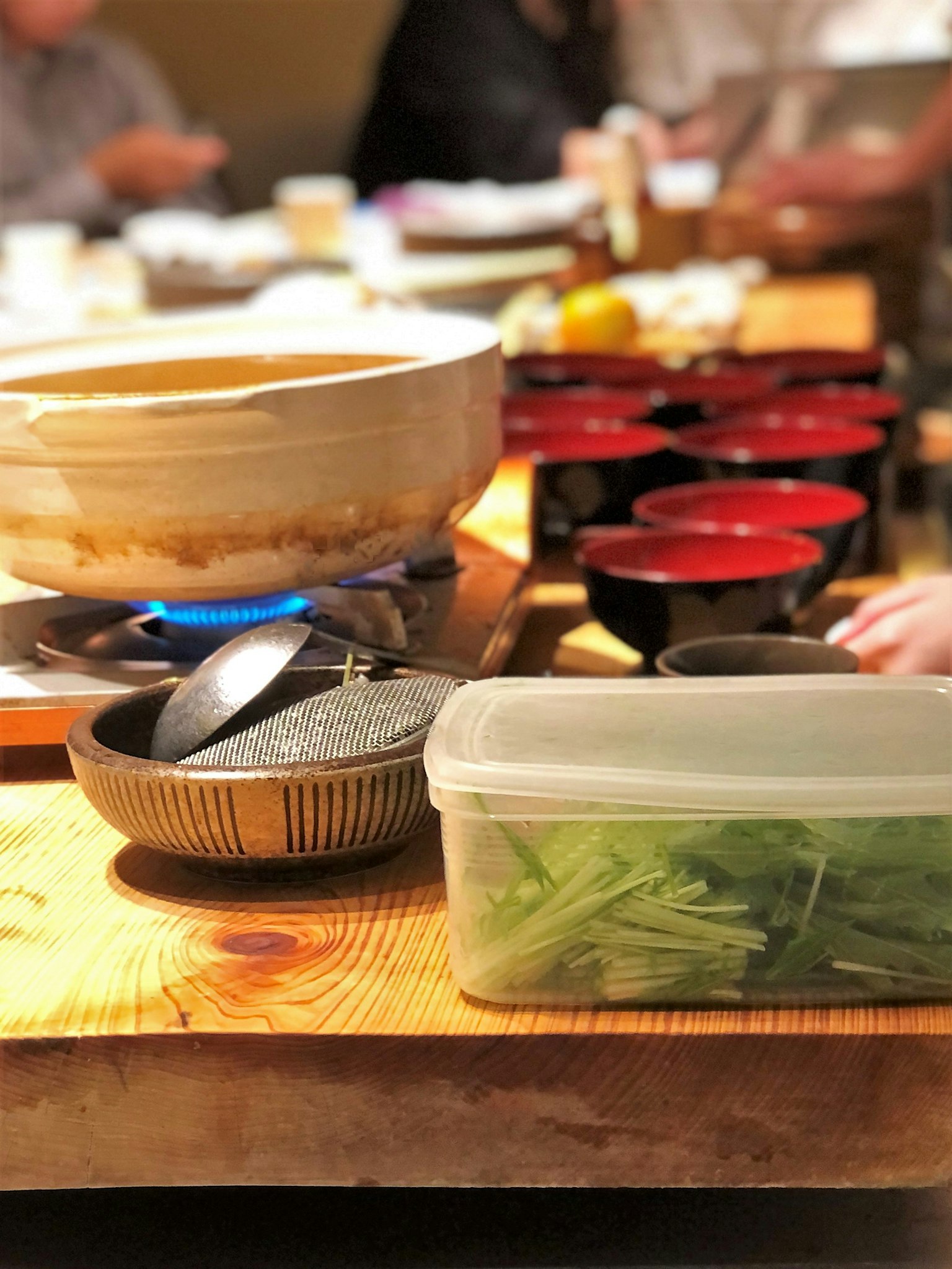 Table avec un plat chaud et des bols rouges Divers légumes et ustensiles de cuisine exposés