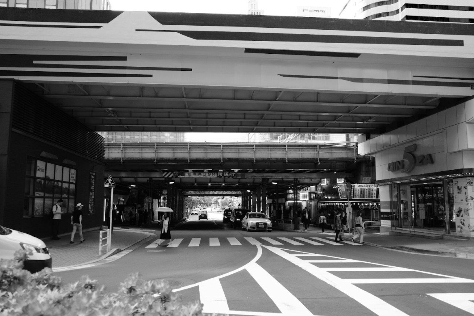 Black and white urban scene featuring a busy intersection and storefronts