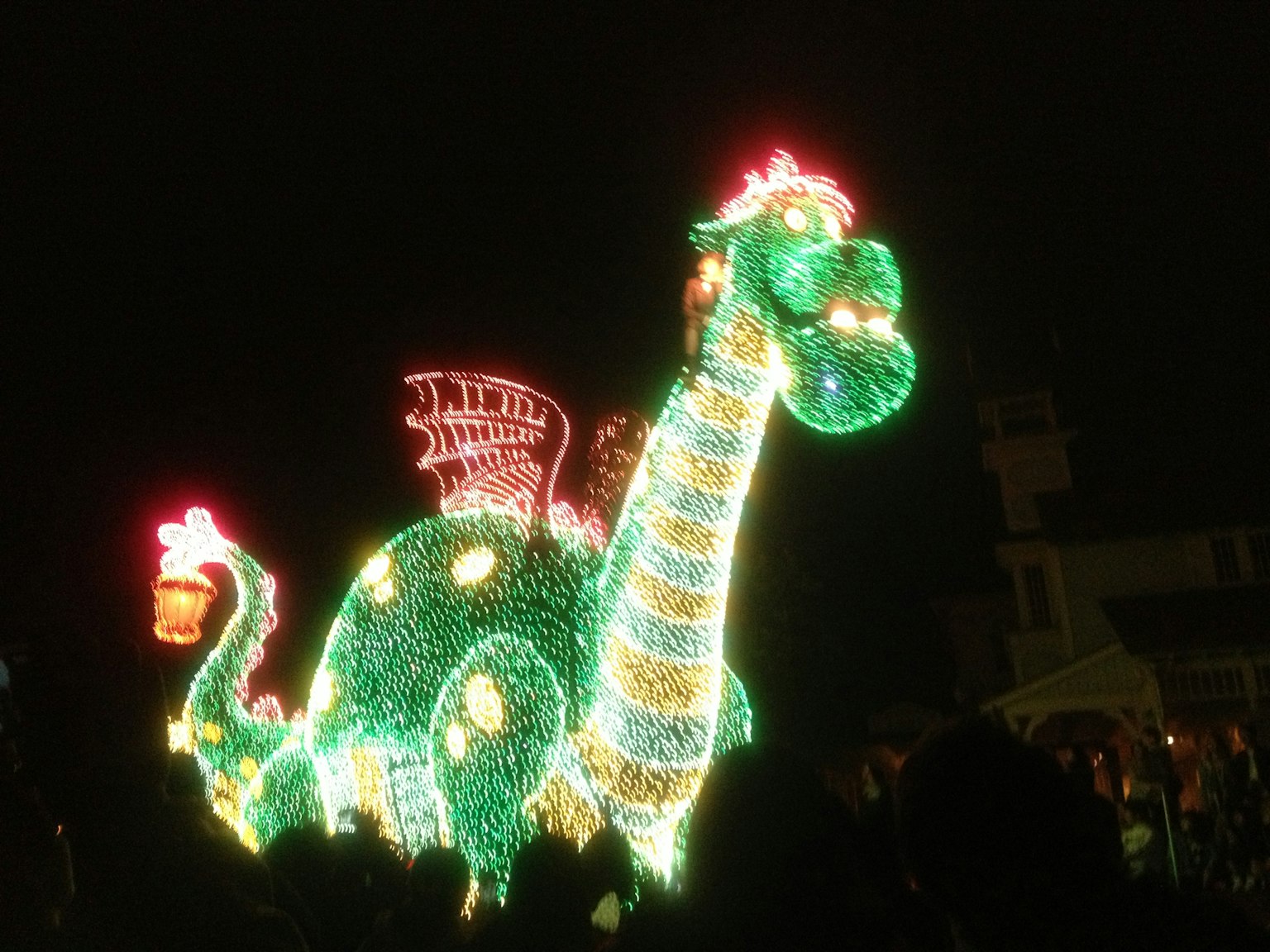 A green dragon parade float decorated with lights colorful illumination against a night background