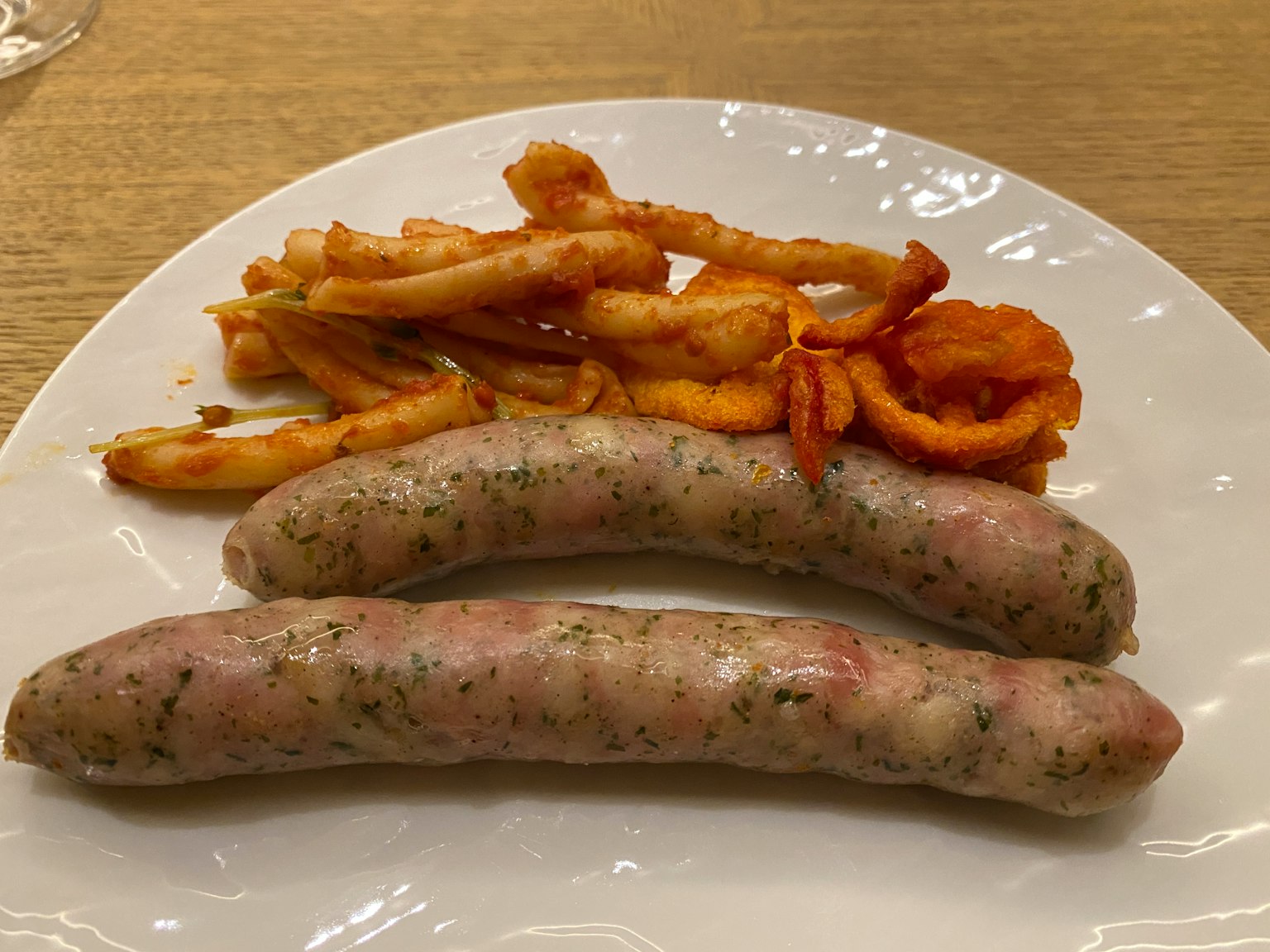 Deux saucisses et des frites sur une assiette blanche
