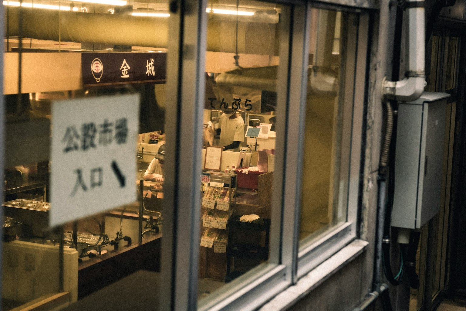 Entrance sign of a public market visible through a window with interior view