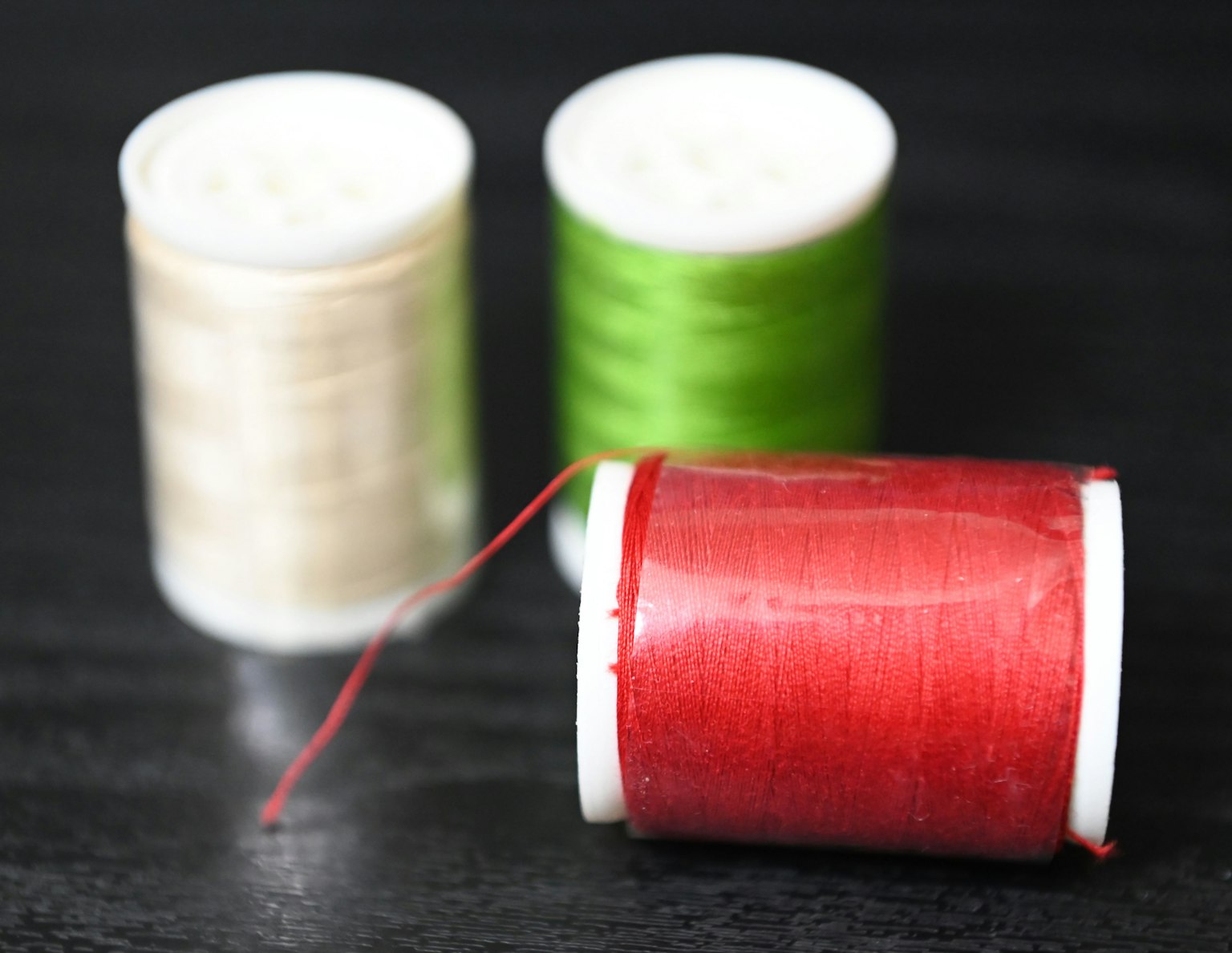 Immagine di rocchetti di filo rosso, verde e crema