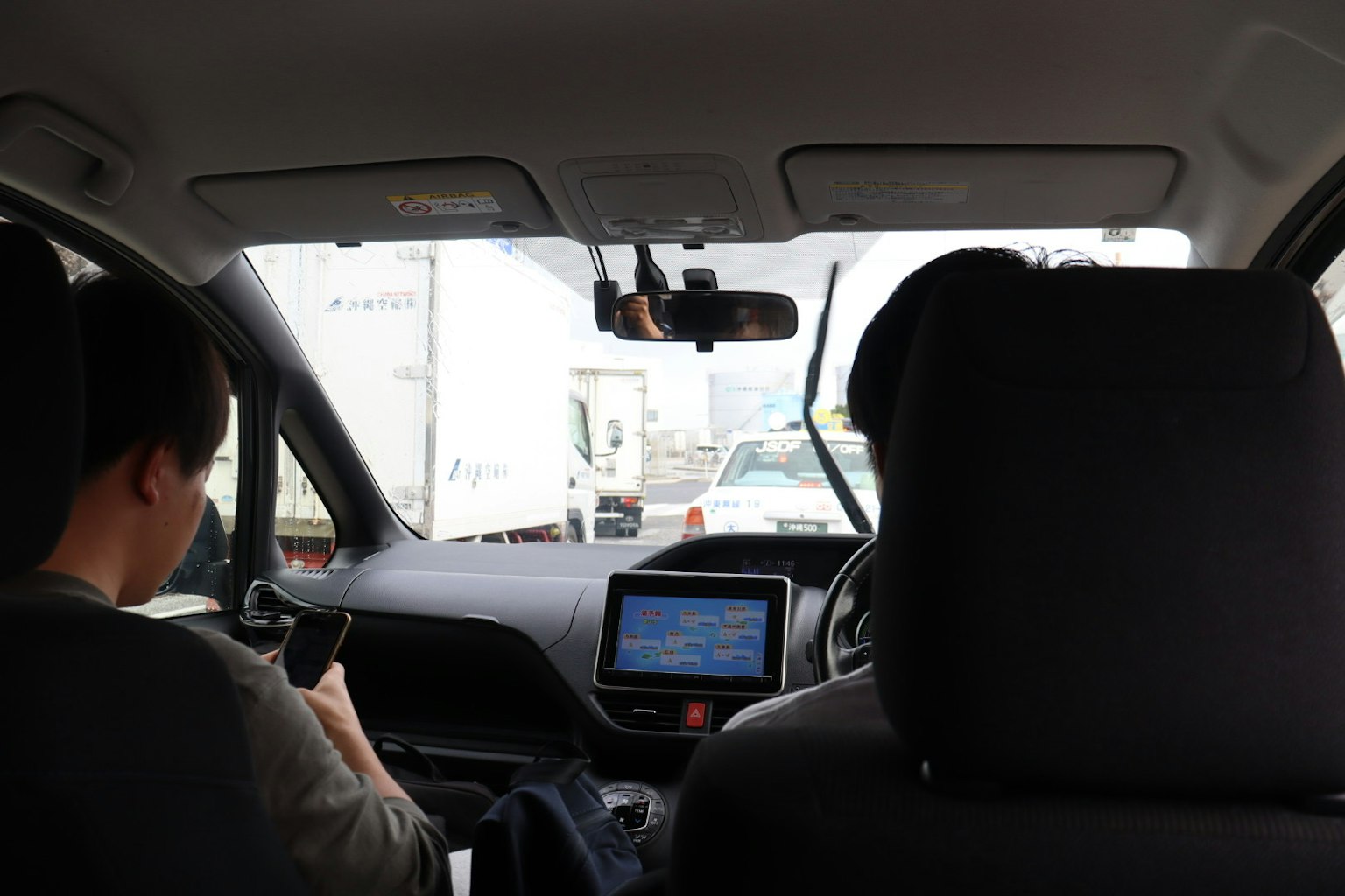 Vista dall'interno di un'auto che mostra due persone e un ingorgo davanti con un sistema di navigazione