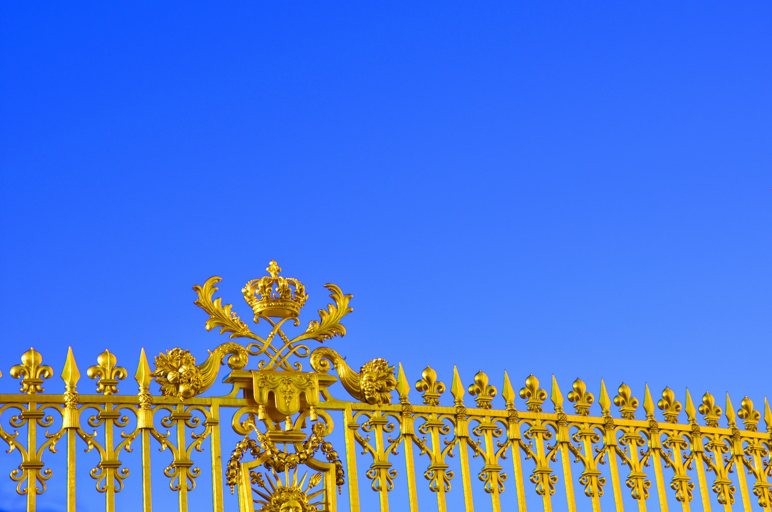 Recinzione dorata e lussuosa con design ornati contro un cielo blu