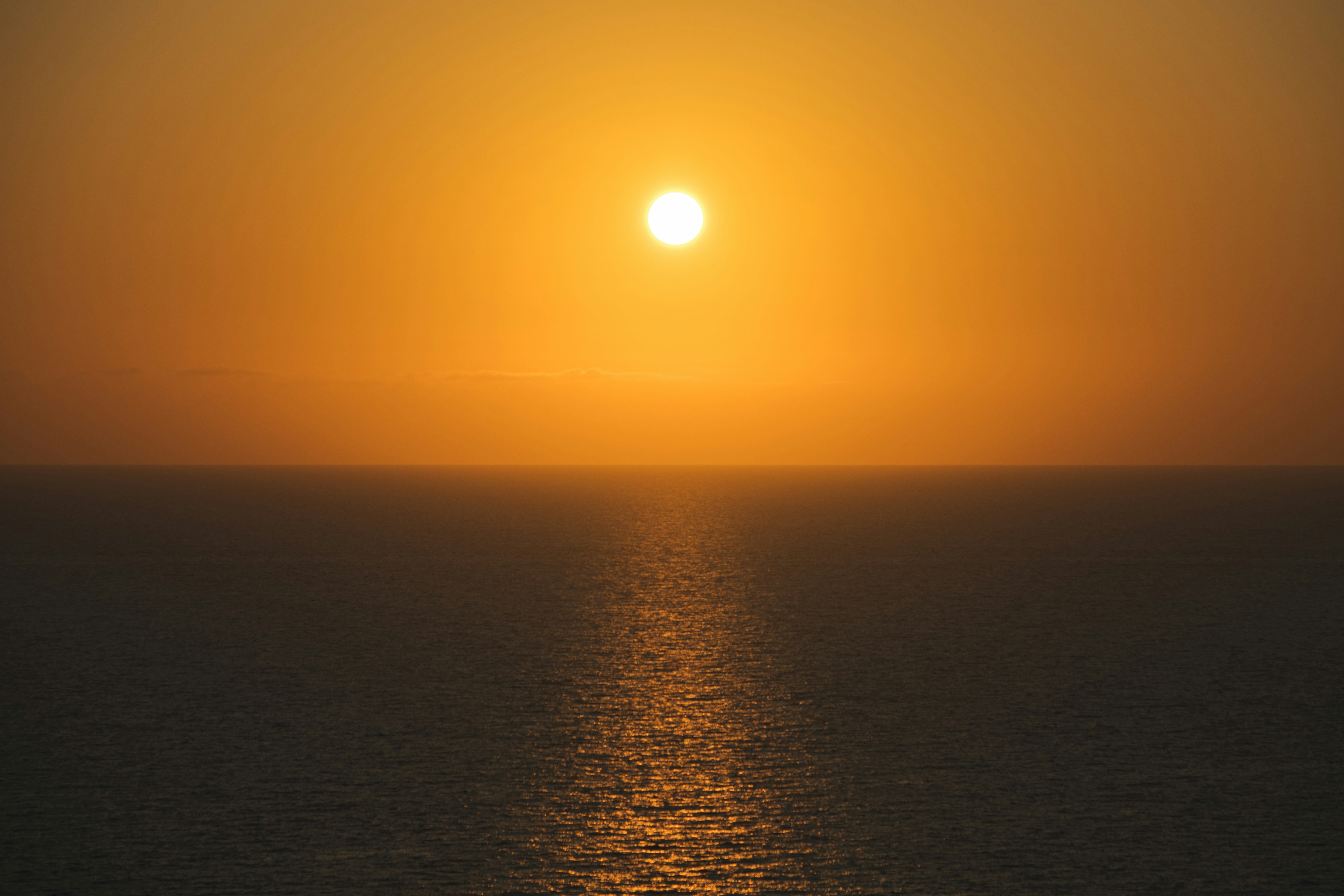 水平線に沈む夕日と海面の光の道