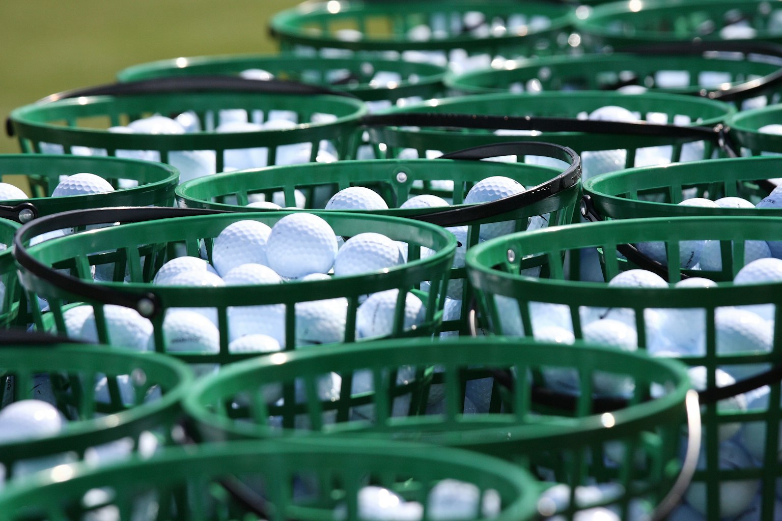 File di palline da golf bianche in cestini verdi