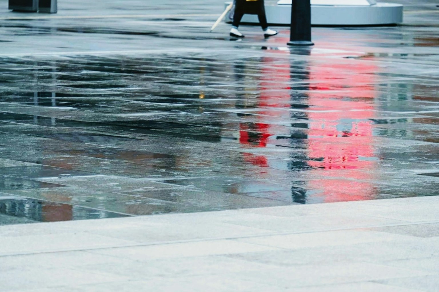 Một người đi bộ trên bề mặt ướt phản chiếu một biển báo đỏ