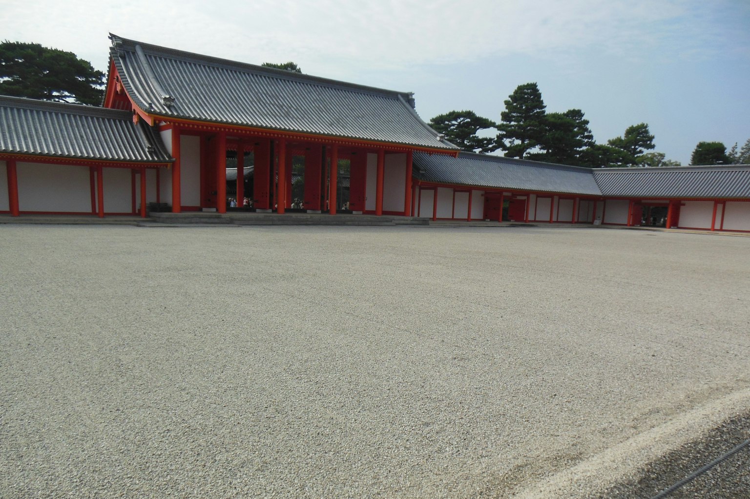 Traditional Japanese building with red pillars and a spacious gravel courtyard