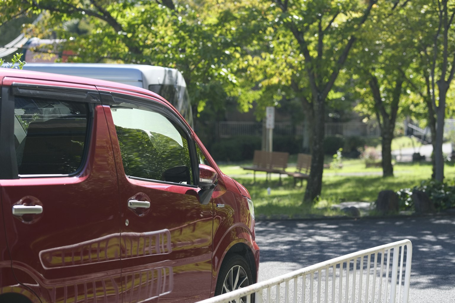 紅色汽車停在綠樹環繞的公園附近