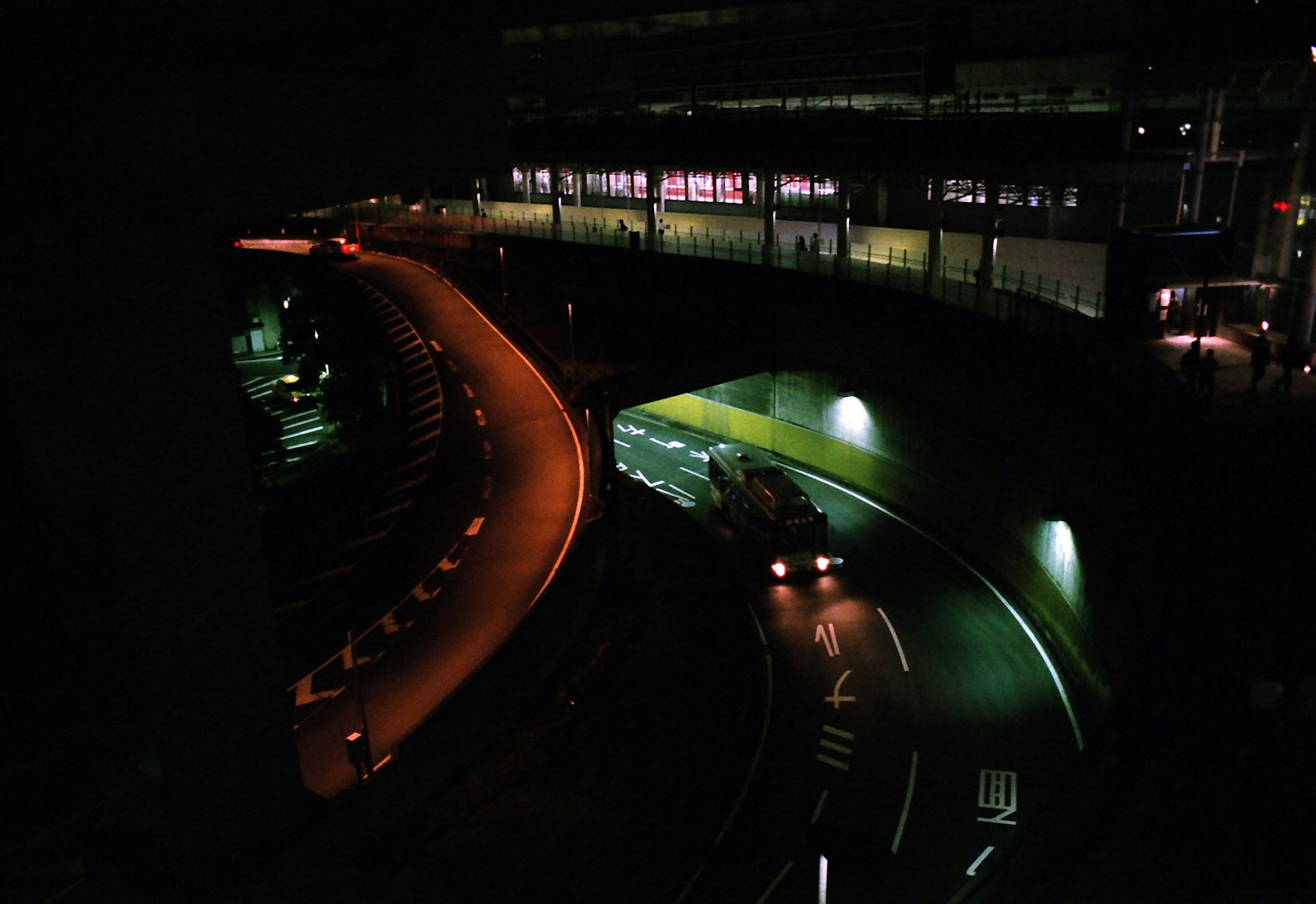 Kurvenreiche Straße bei Nacht mit lebendiger Beleuchtung und städtischer Landschaft
