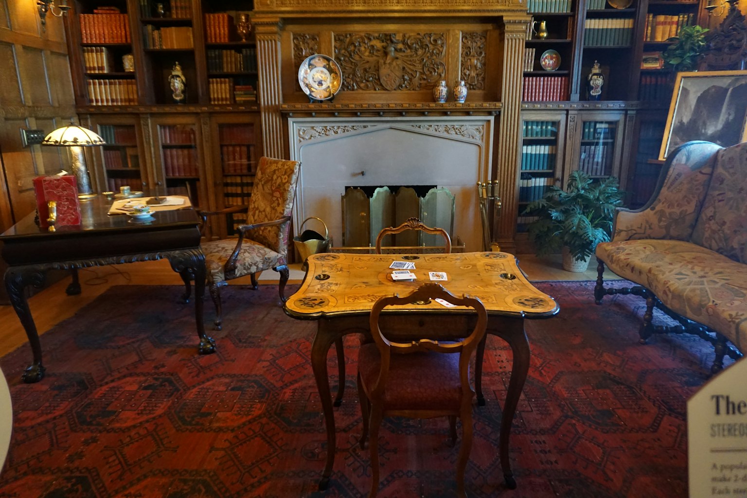 Intérieur d'un bureau élégant avec des étagères décoratives et une table en bois près de la cheminée avec des chaises
