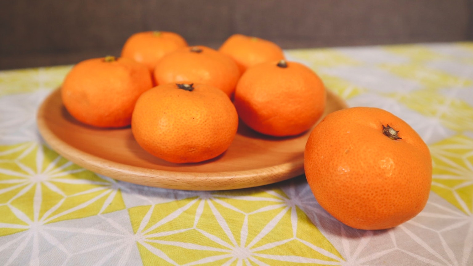 Une assiette de mandarines oranges sur une nappe à motifs