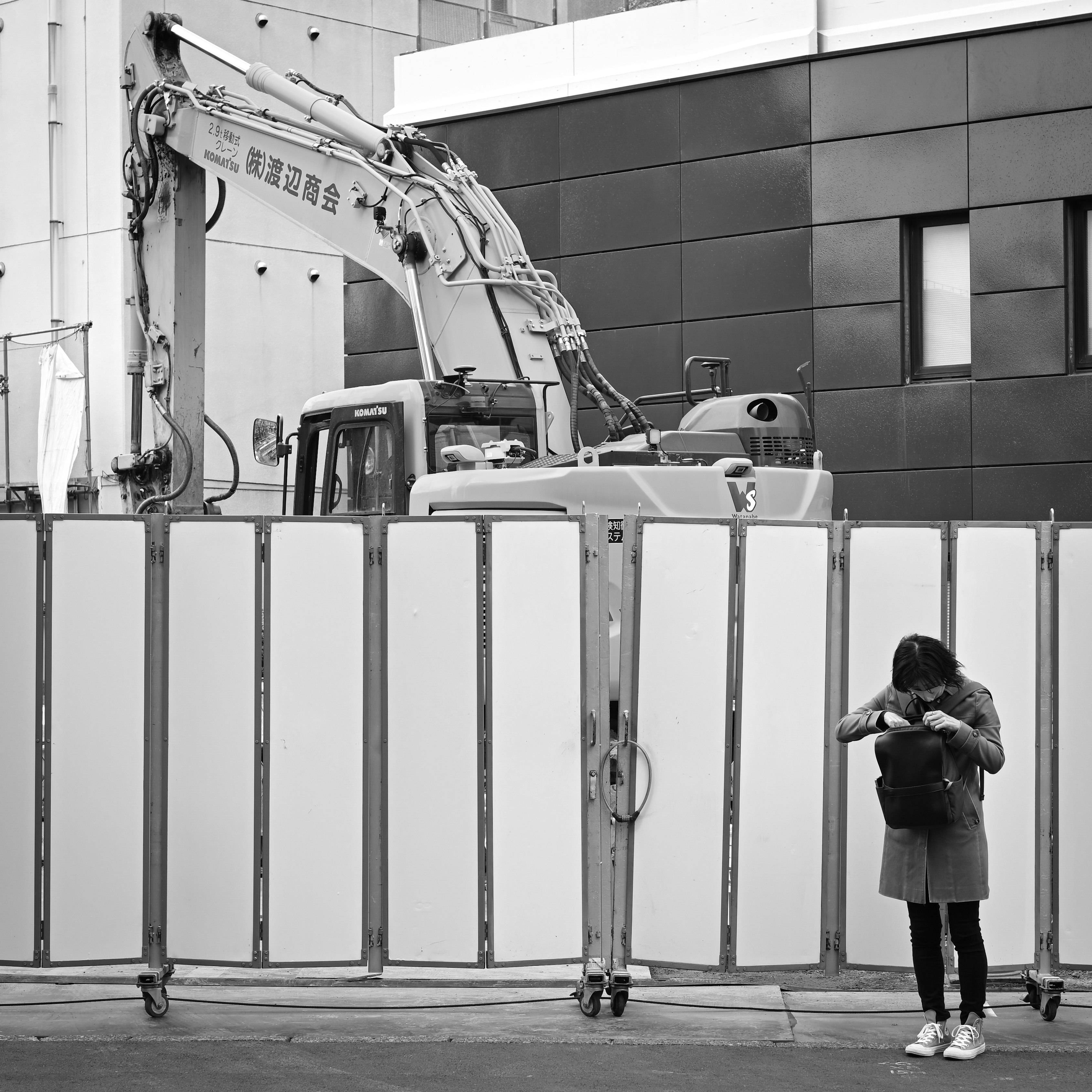 construction site crane and heavy machinery behind a fence with a person