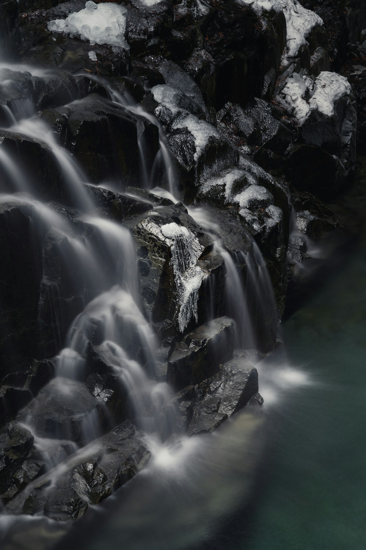 流動的瀑布在岩石上，背景深色，水面光滑