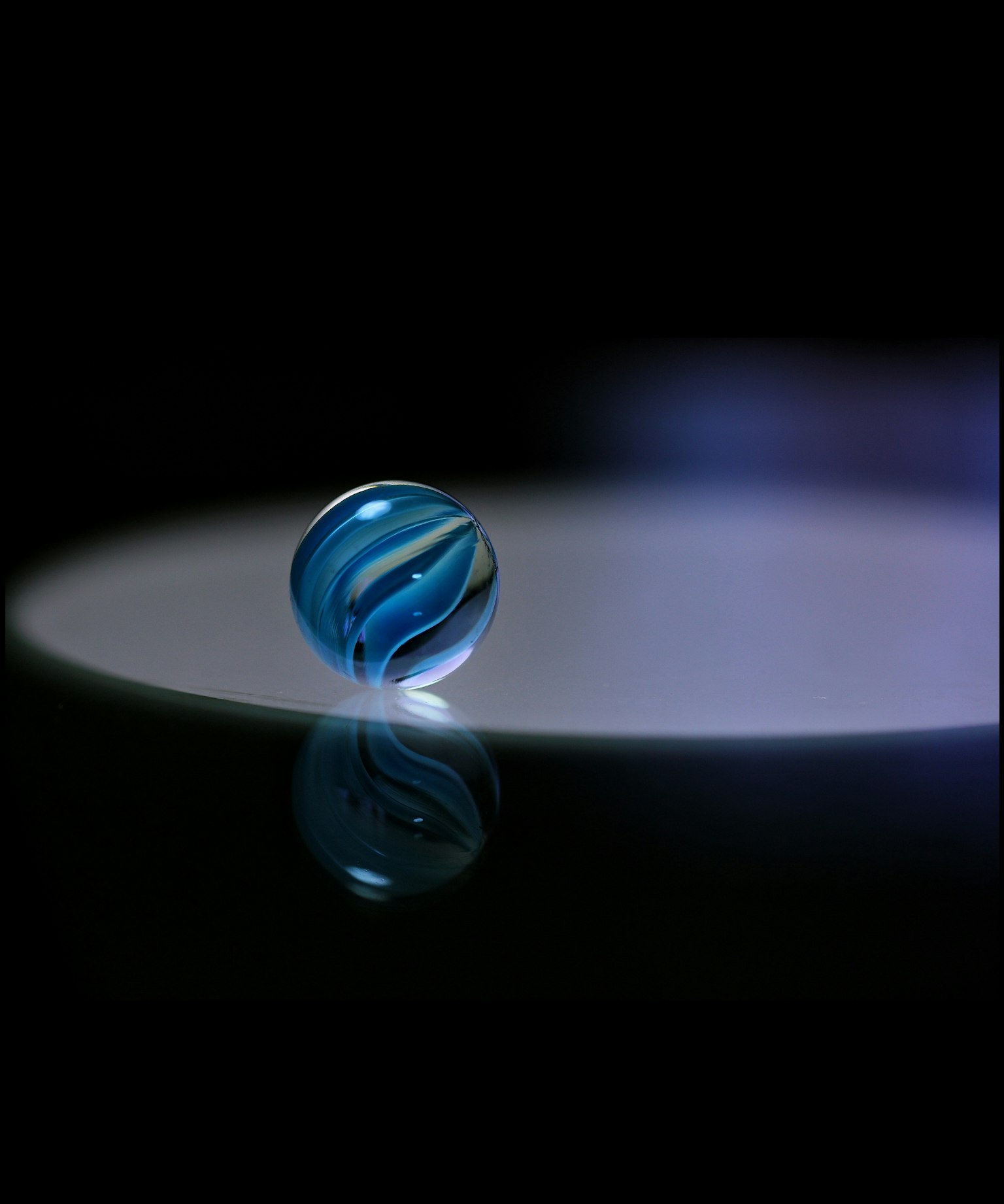 Una canica azul reflejando luz sobre una superficie