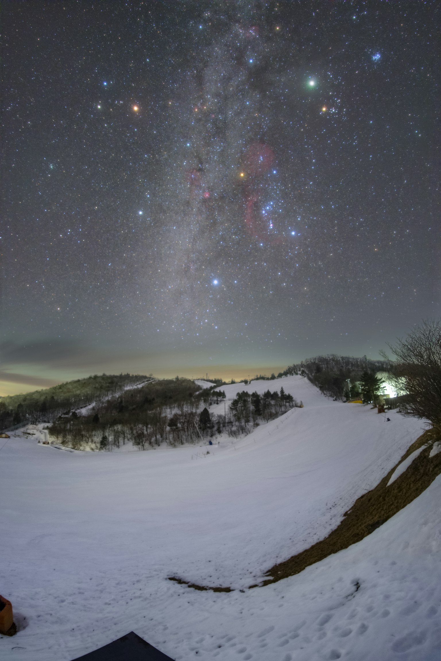 Foto panorámica de un paisaje nevado y un cielo estrellado con la Vía Láctea y la constelación de Orión