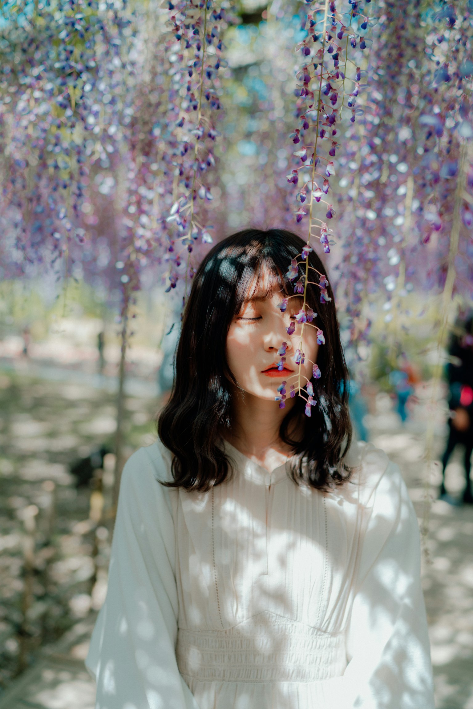 Ritratto di una donna che sorride sotto fiori viola pendenti