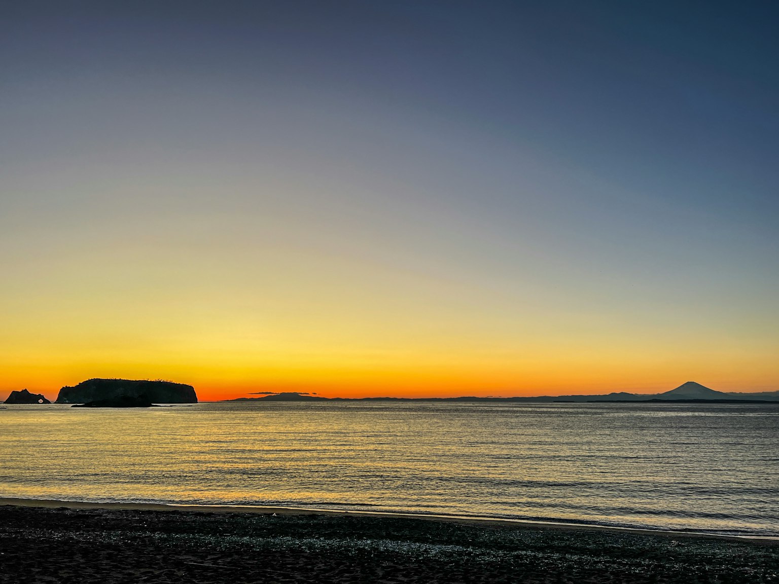 Splendido tramonto che illumina il mare con una montagna in lontananza