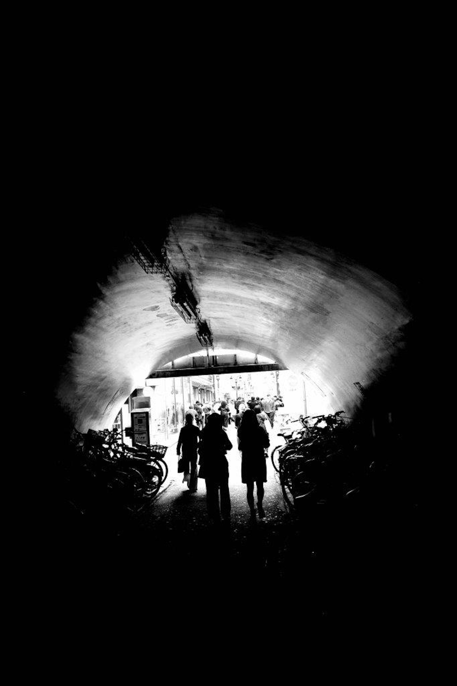 Siluetas de personas de pie en un túnel con una salida brillante