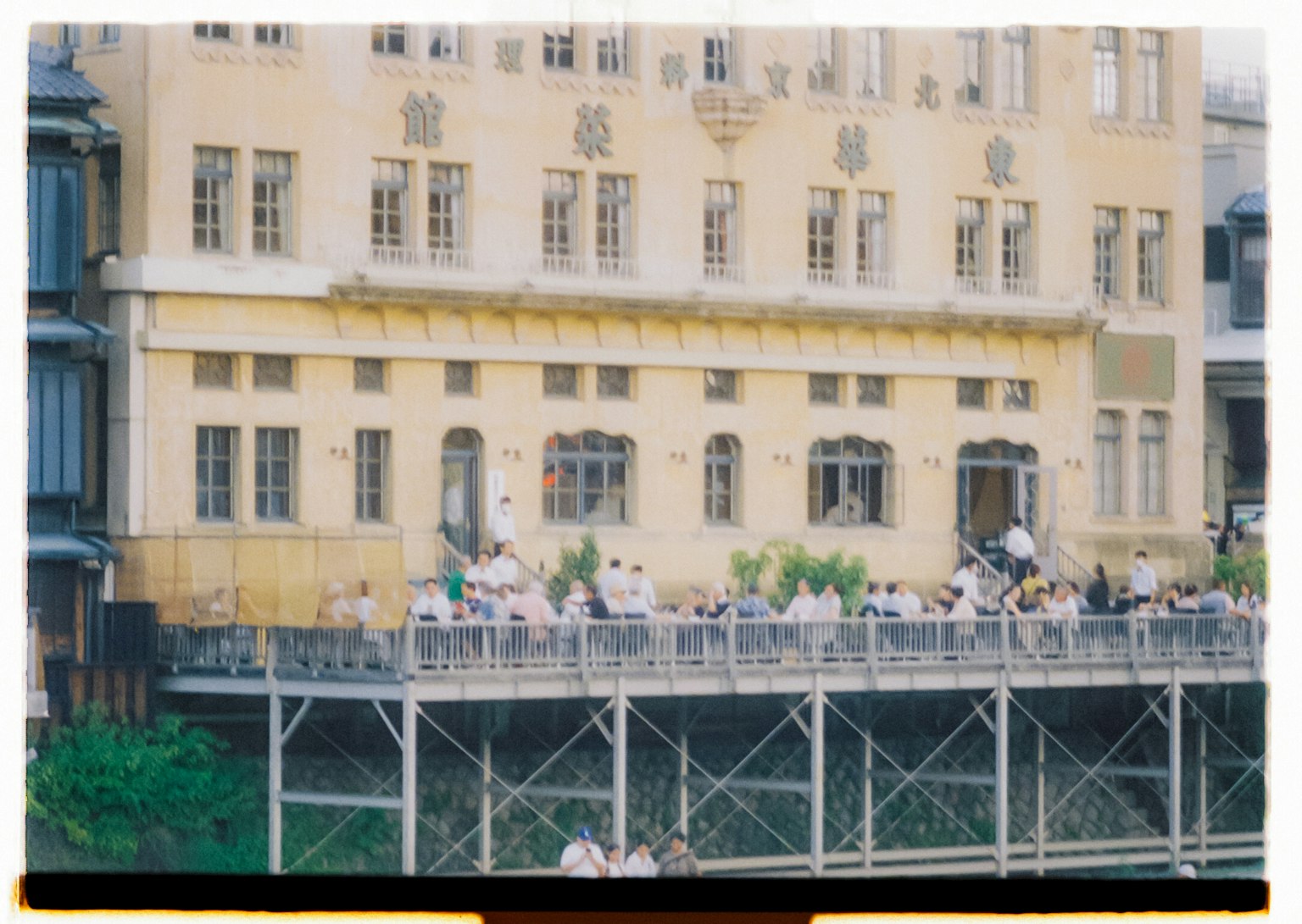 Historisches Gebäude mit Menschen auf einer Terrasse am Fluss