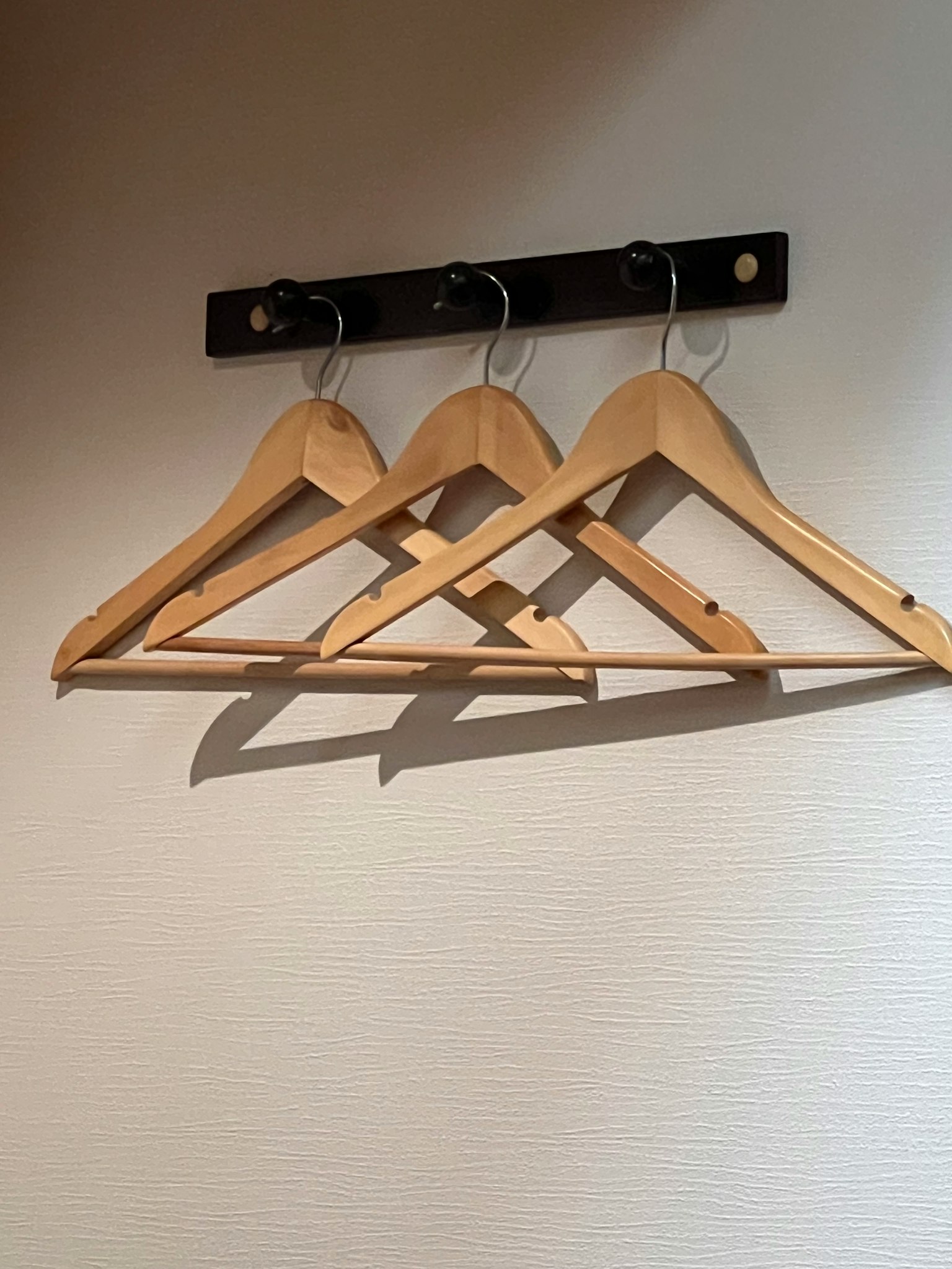 Simple image of wooden hangers hanging on a wall