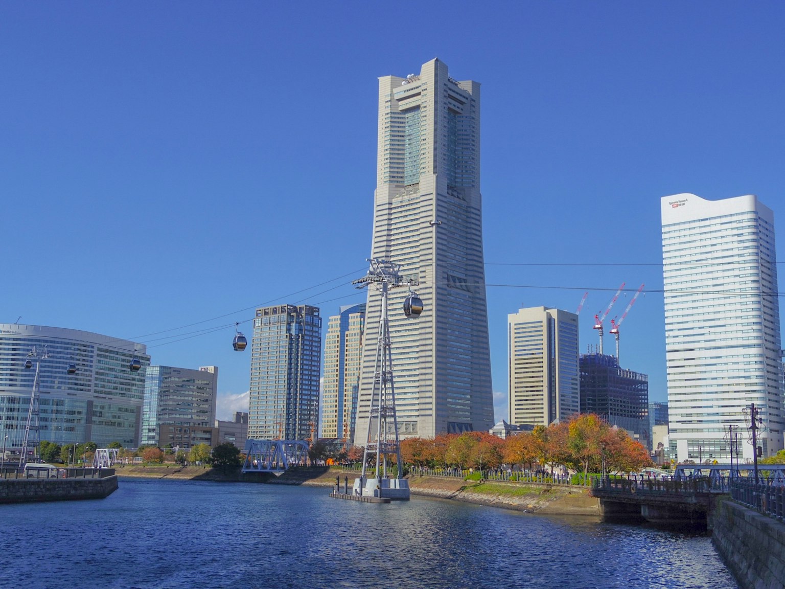 Skyline von Yokohama mit hohen Gebäuden und einer Seilbahn über dem Wasser