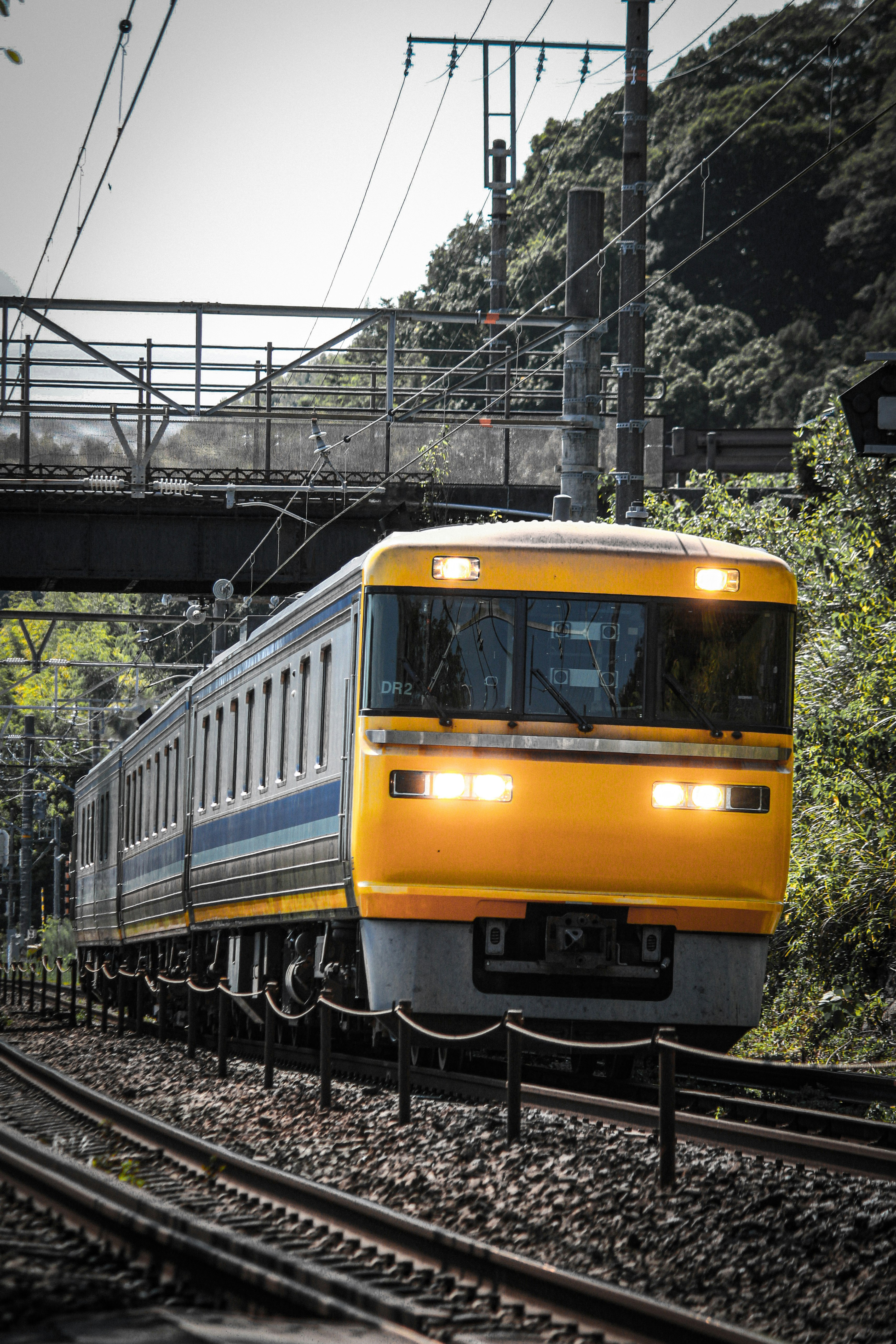 yellow train running on tracks through a mountainous area