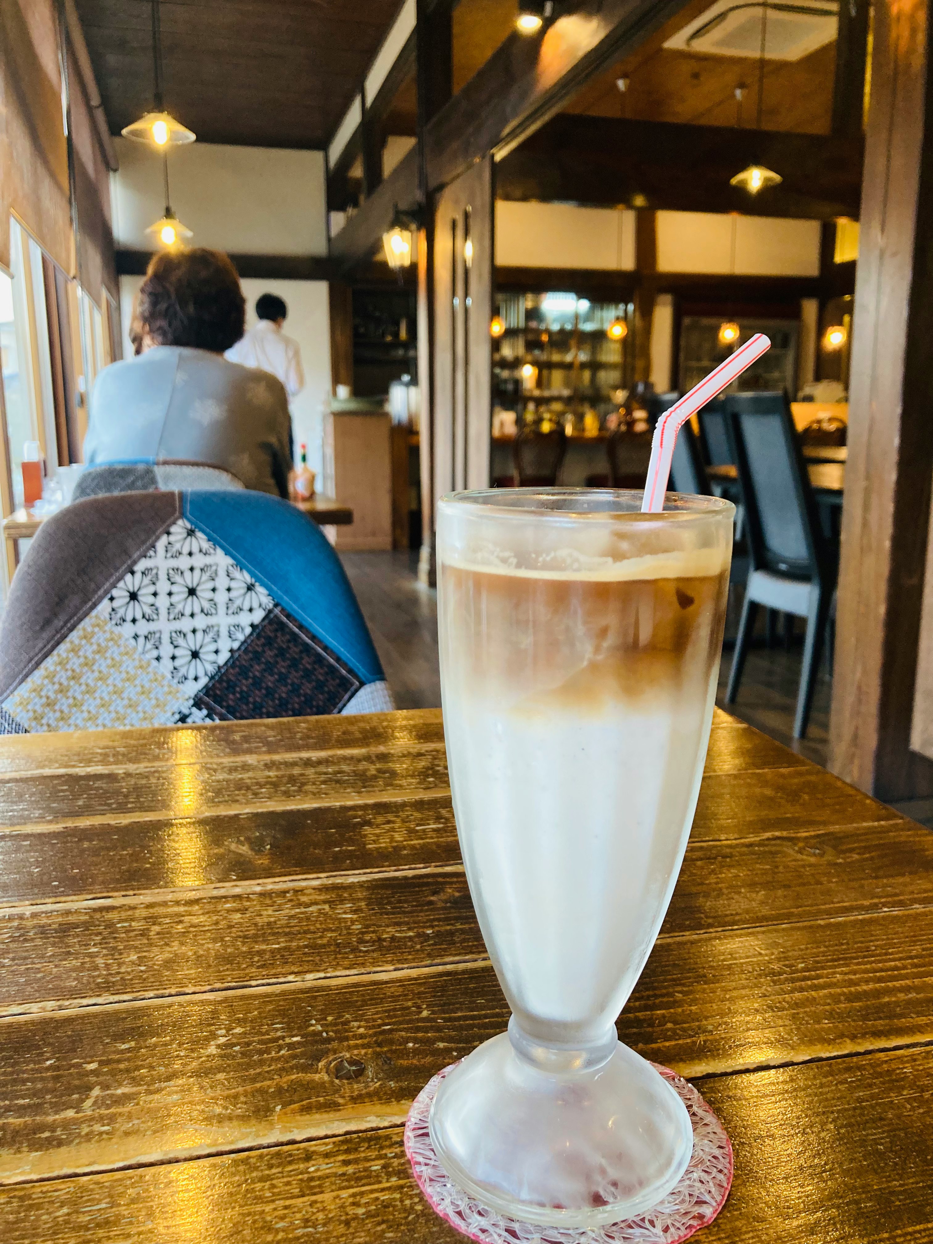 glass of iced latte on a wooden café counter inside a coffee shop