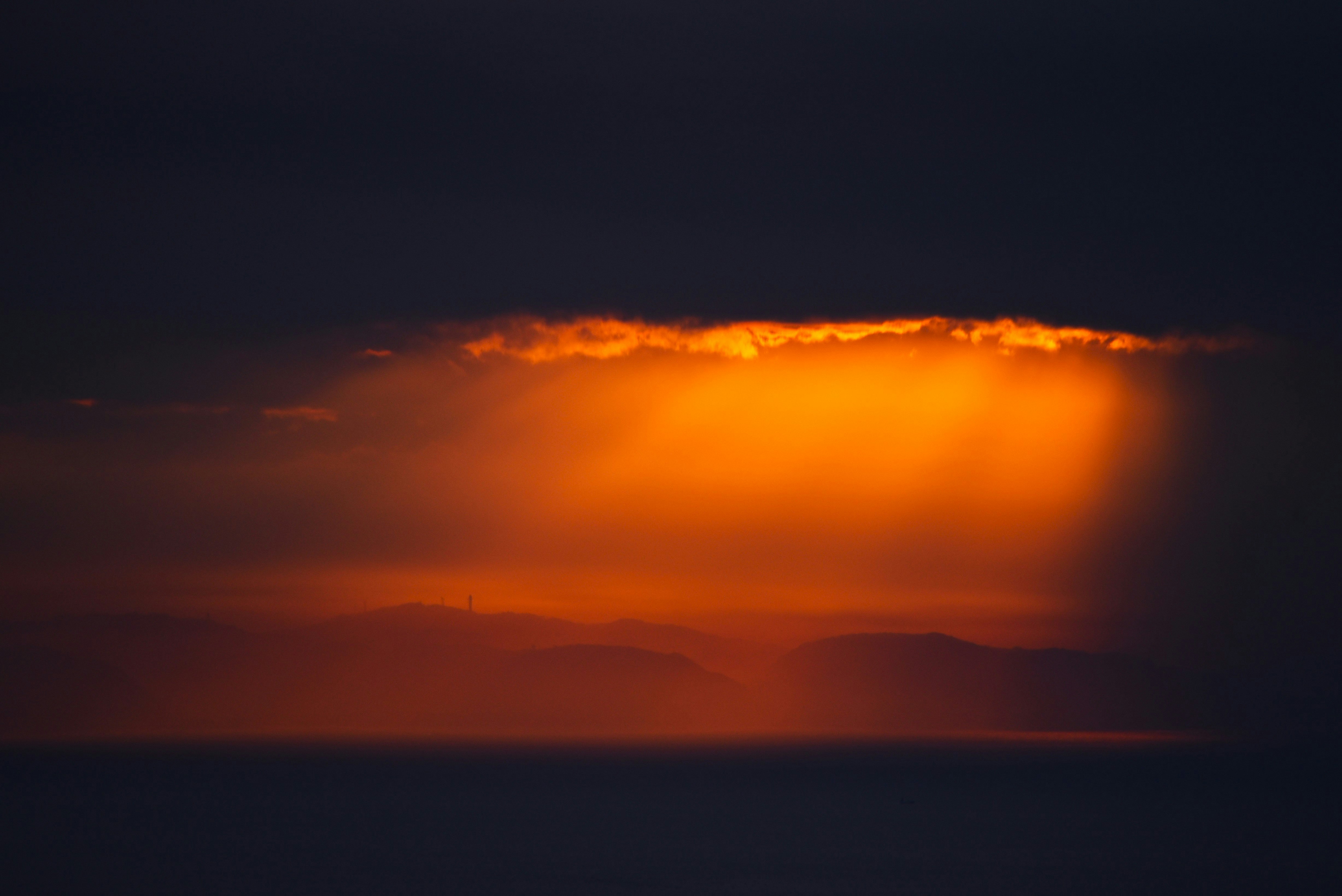 夕暮れの海に浮かぶ島影と降り注ぐ光