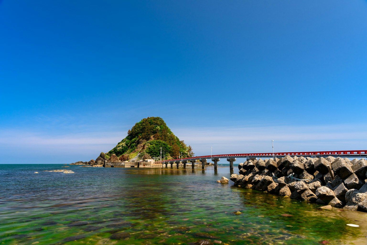 Pemandangan indah pulau kecil dengan dermaga dikelilingi langit dan air biru