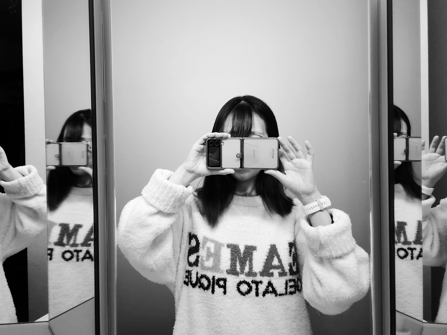 Femme prenant un selfie devant des miroirs portant un sweat-shirt blanc se reflétant dans plusieurs miroirs