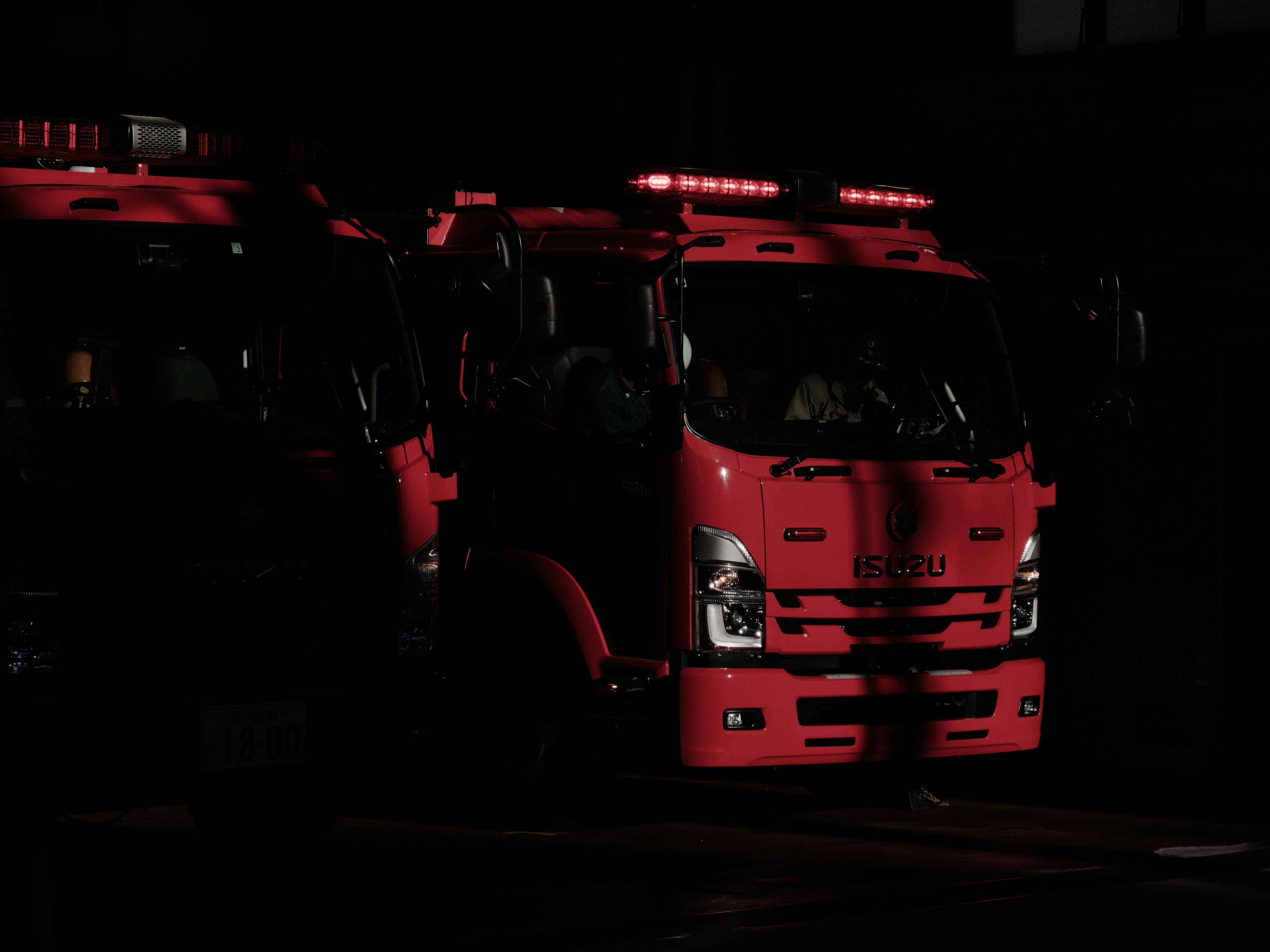 赤い消防車が出動準備をしている夜の街並み