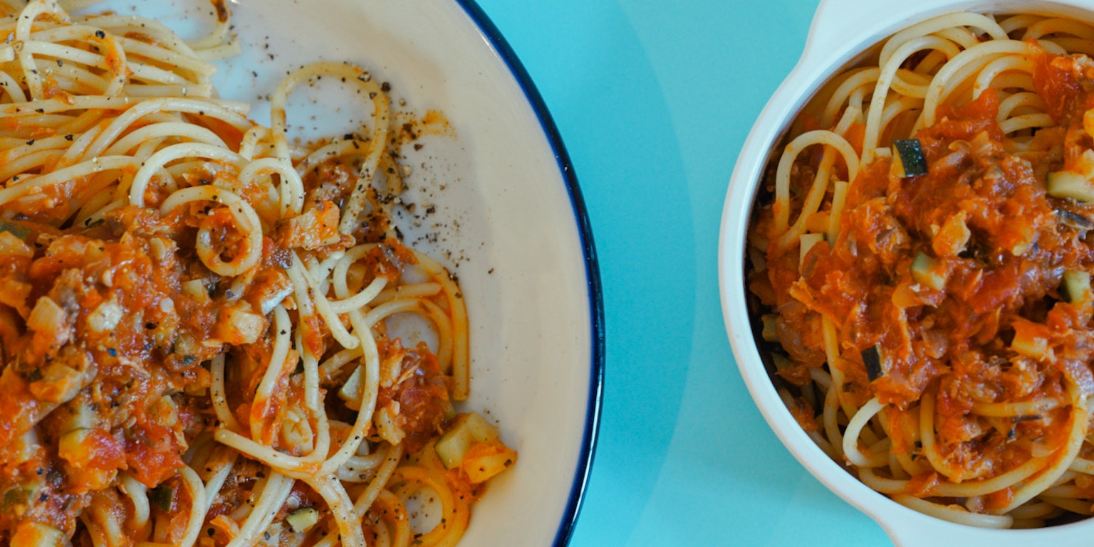 Spaghetti mit Tomatensauce auf einem Teller vor blauem Hintergrund