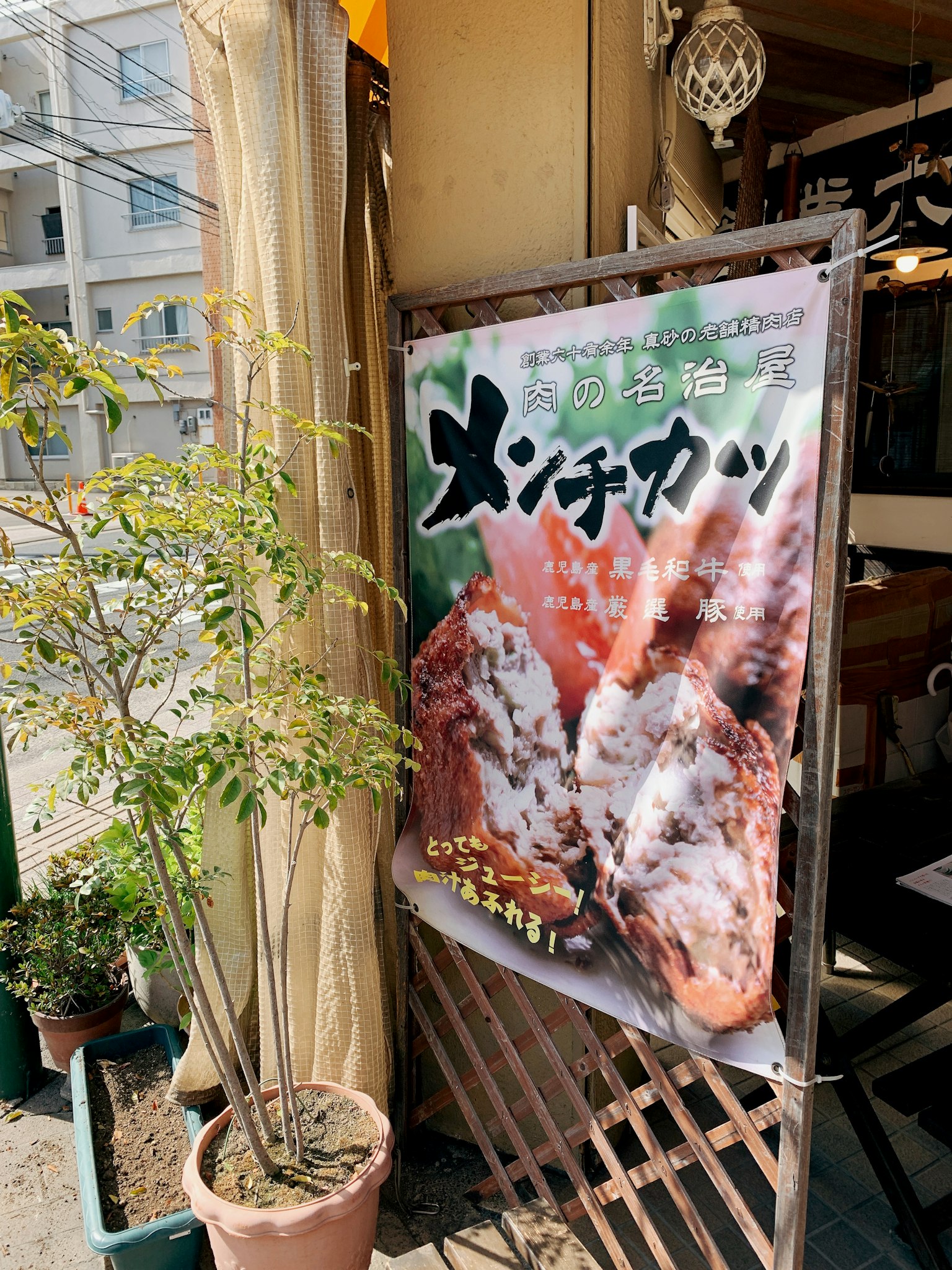 A restaurant sign featuring large images of menchi katsu