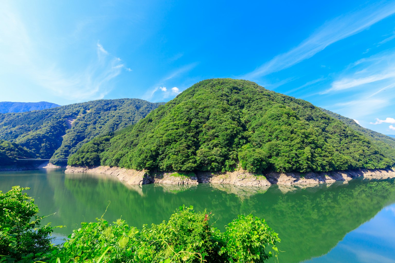 Vista escénica de una montaña cubierta de verde con un lago tranquilo