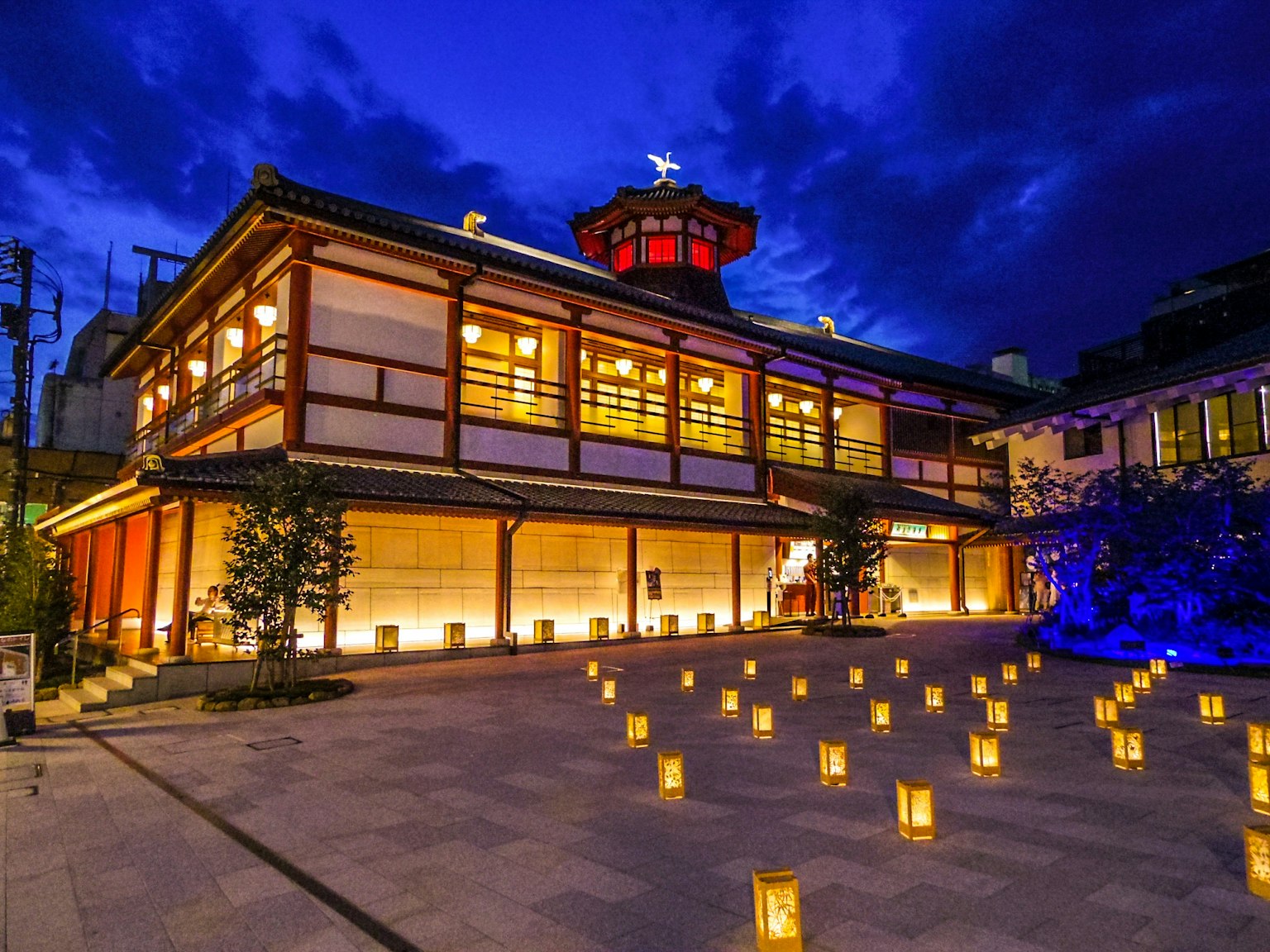 Bangunan tradisional Jepang yang diterangi di malam hari di bawah langit biru