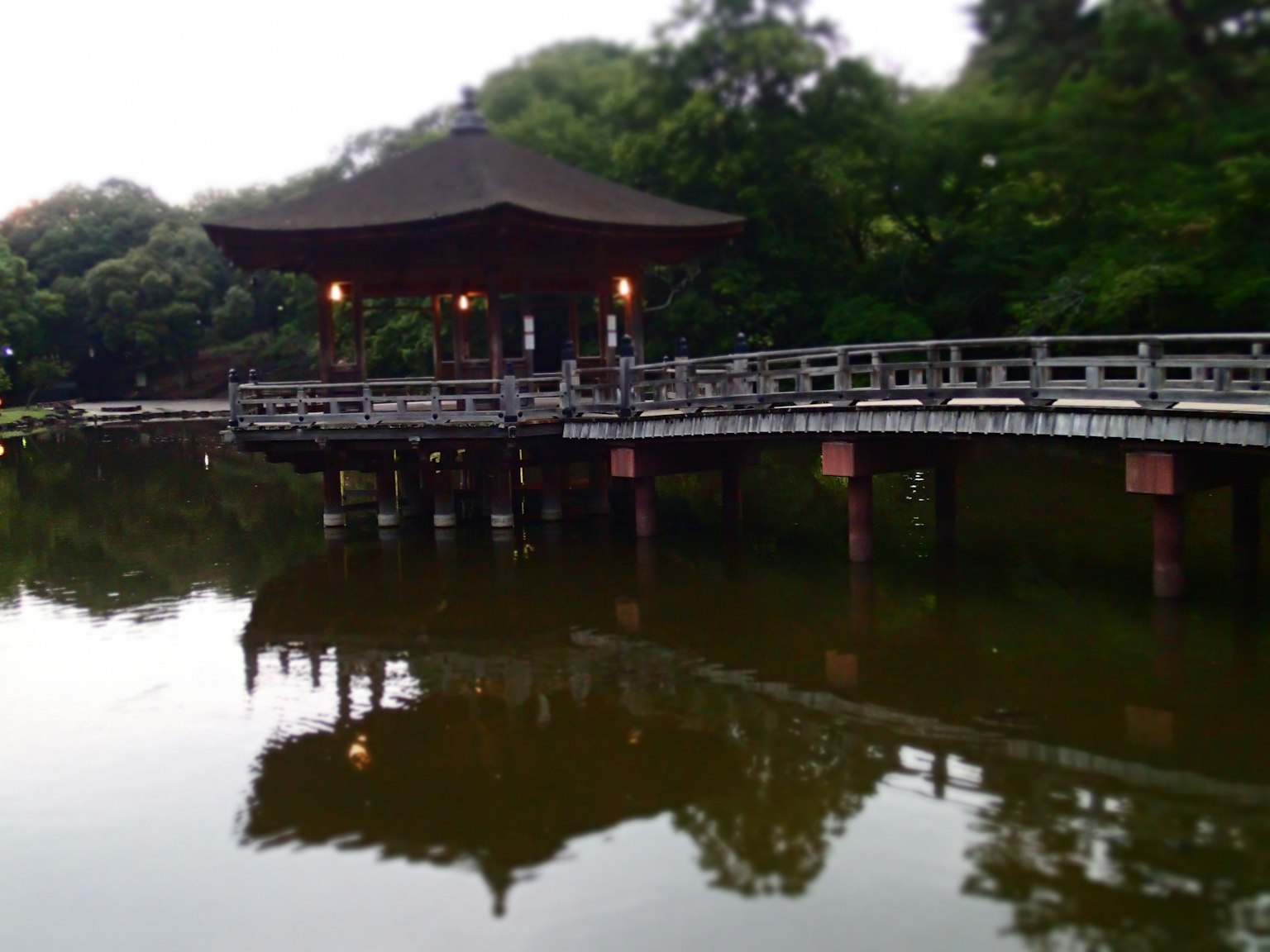 Traditionelles japanisches Pavillon über einem ruhigen Teich mit einer Holzbrücke