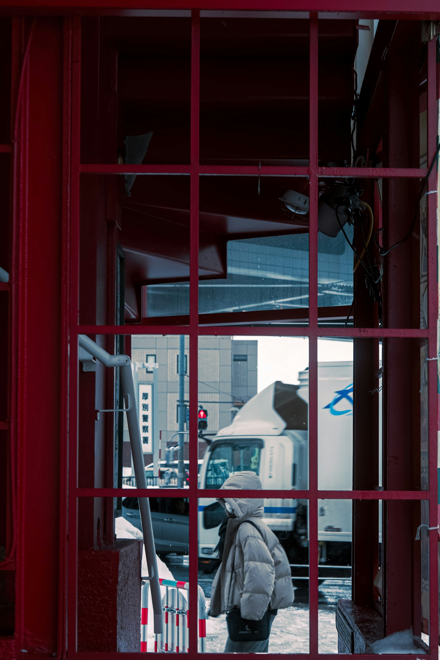 Vista di un paesaggio urbano e di una persona attraverso la finestra di una cabina telefonica rossa