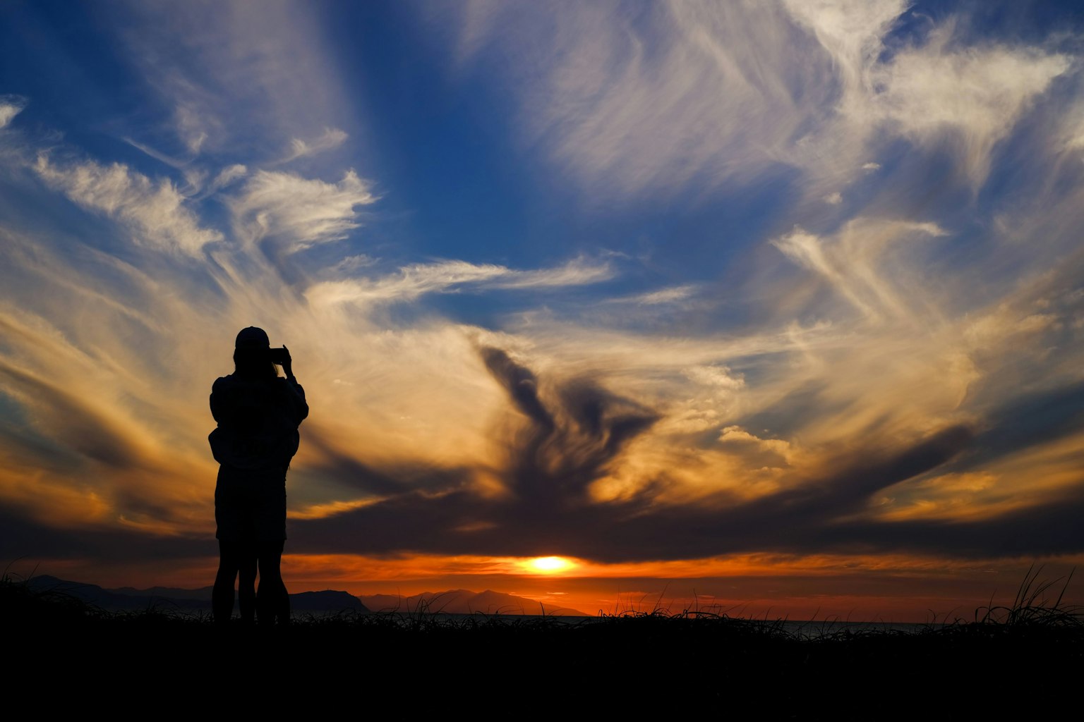 Silhouette of a couple against a sunset with dramatic cloud patterns