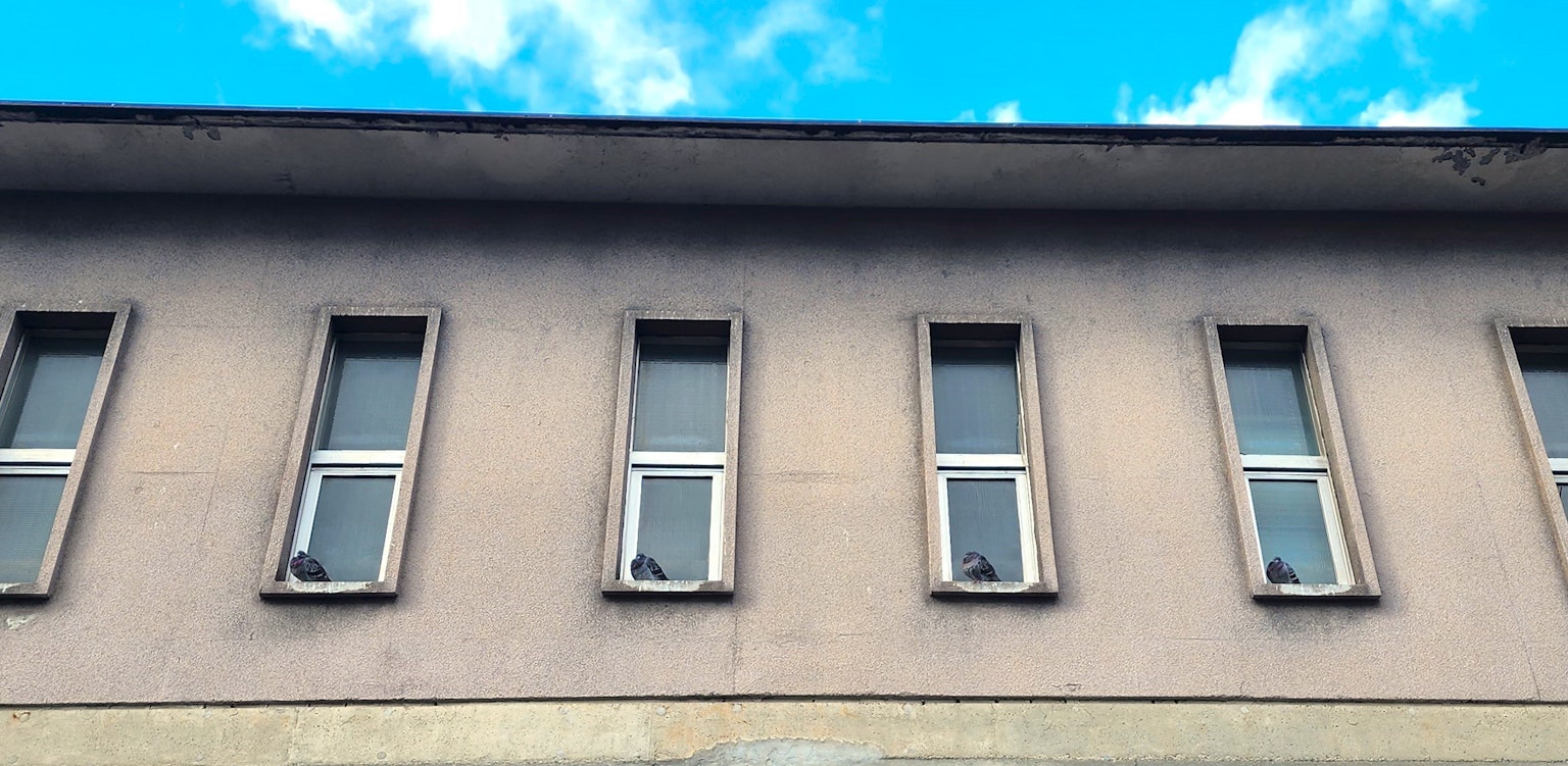 Building wall with four windows under a blue sky